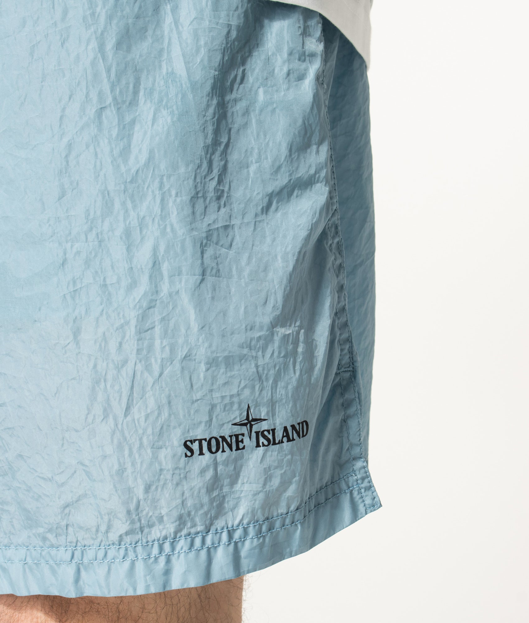 Stone Island Relaxed Fit Water Reactive Faded Camo Swim Shorts in Powder Blue at EQVVS Menswear. Detail shot.