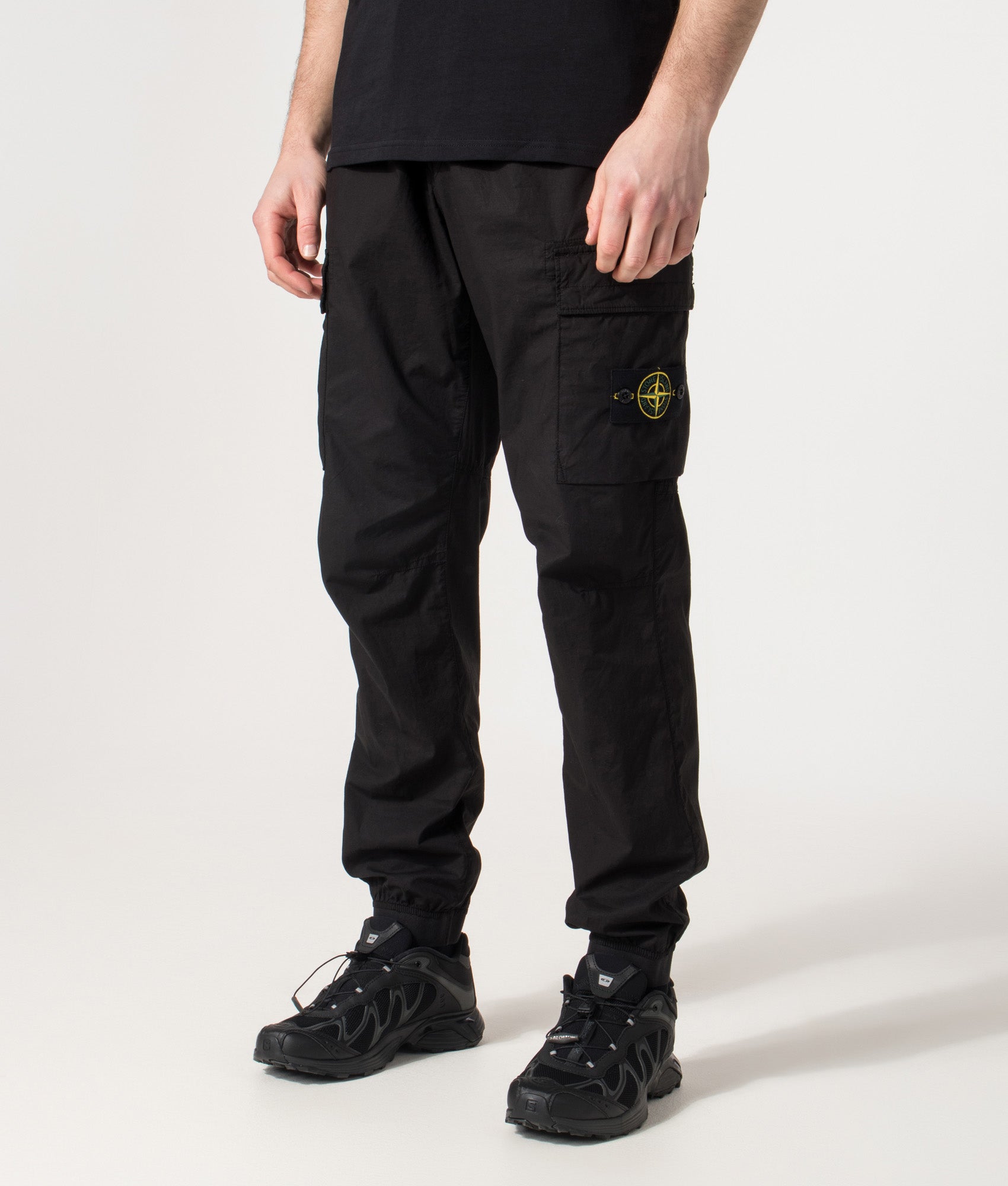 Stone Island Tapered Cargo Pants in Black at EQVVS Menswear. Angled front shot.