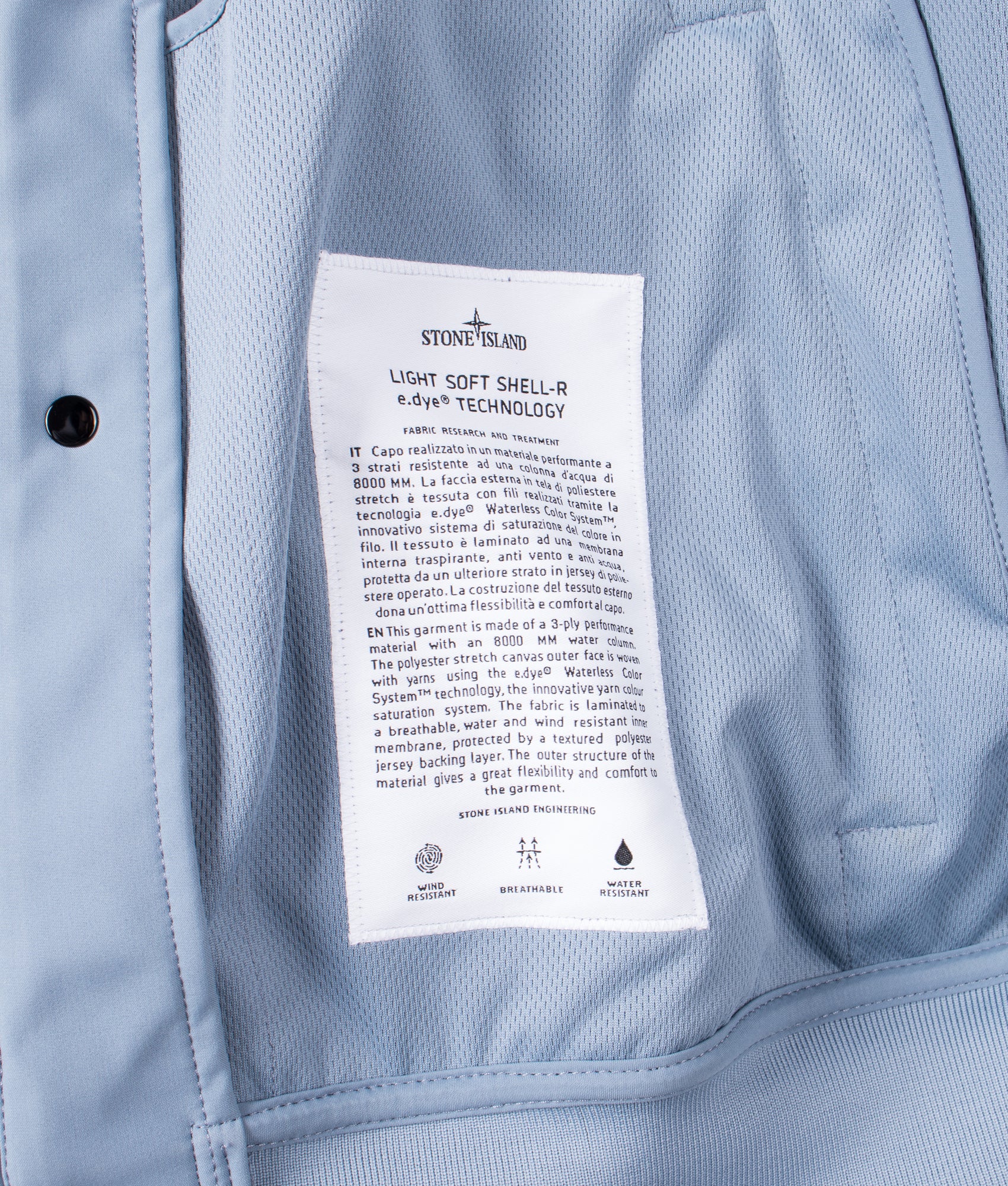 Stone Island release the Light Soft Shell-R E.DYE® Technology Hooded Jacket in Avio Blue at EQVVS Menswear. Label shot.
