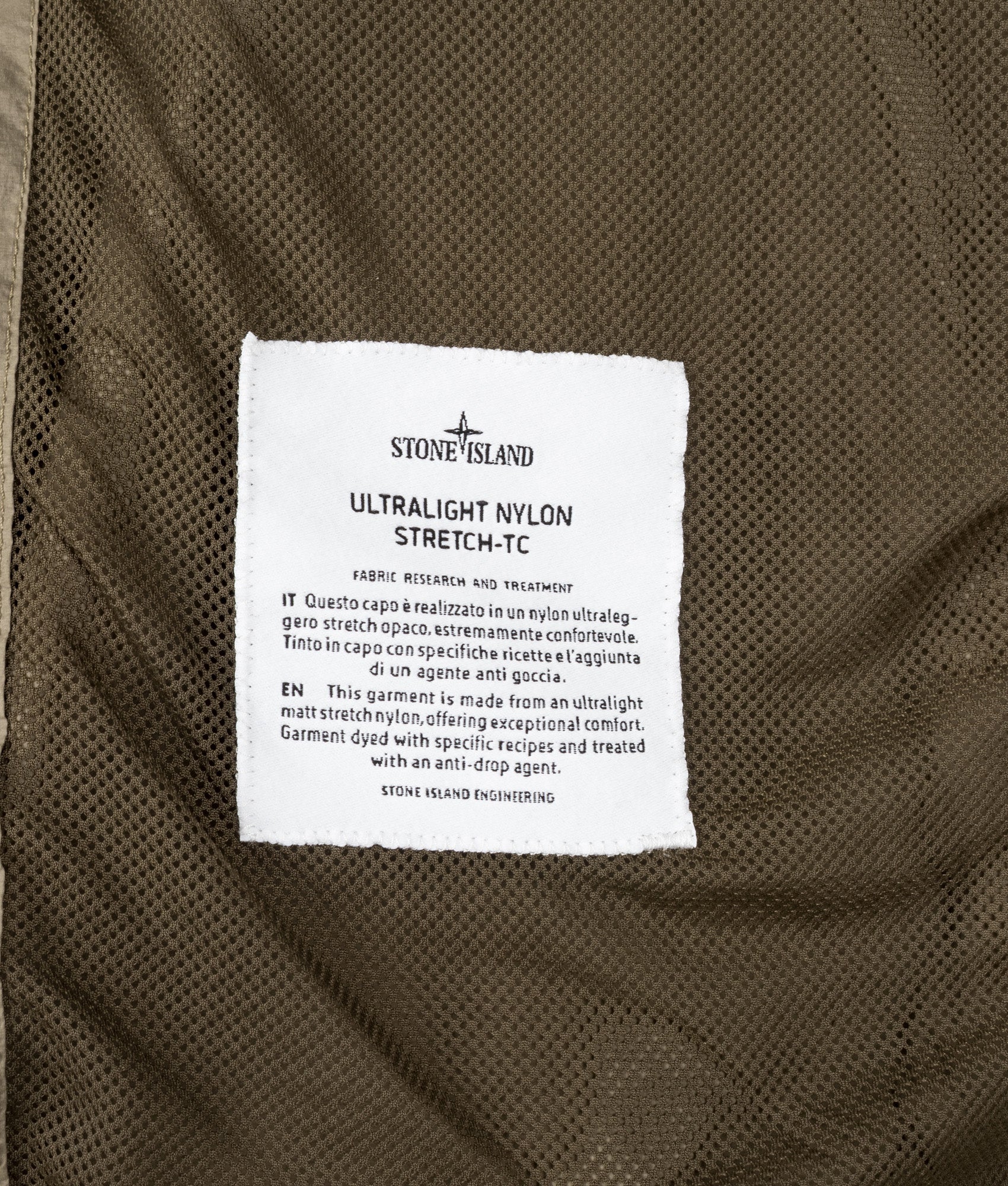 Stone Island Ultralight Nylon Stretch-TC Jacket in Military Green at EQVVS Menswear. Label shot.