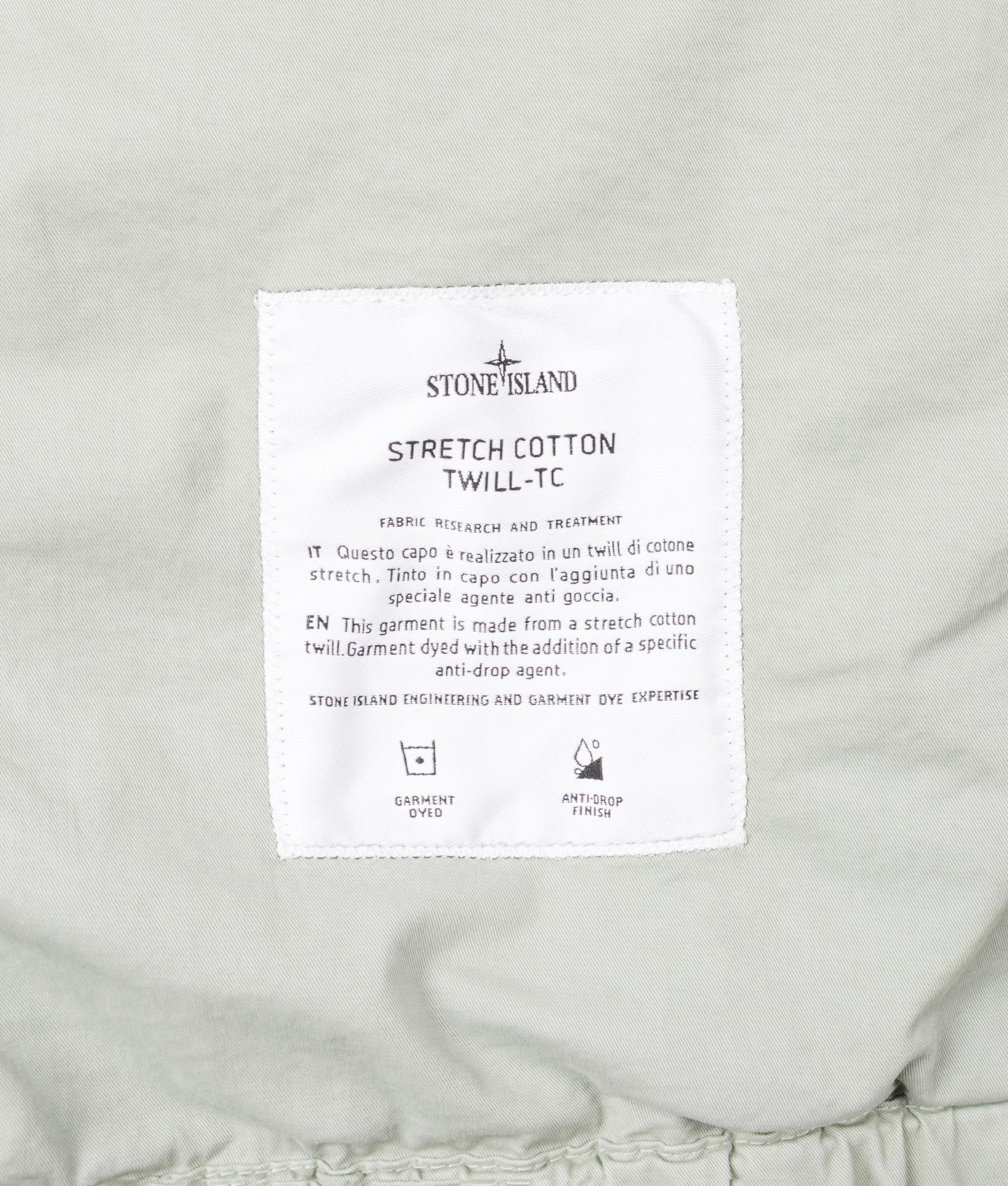 Stone Island Hooded Field Jacket in Sage at EQVVS Menswear. Tag shot.