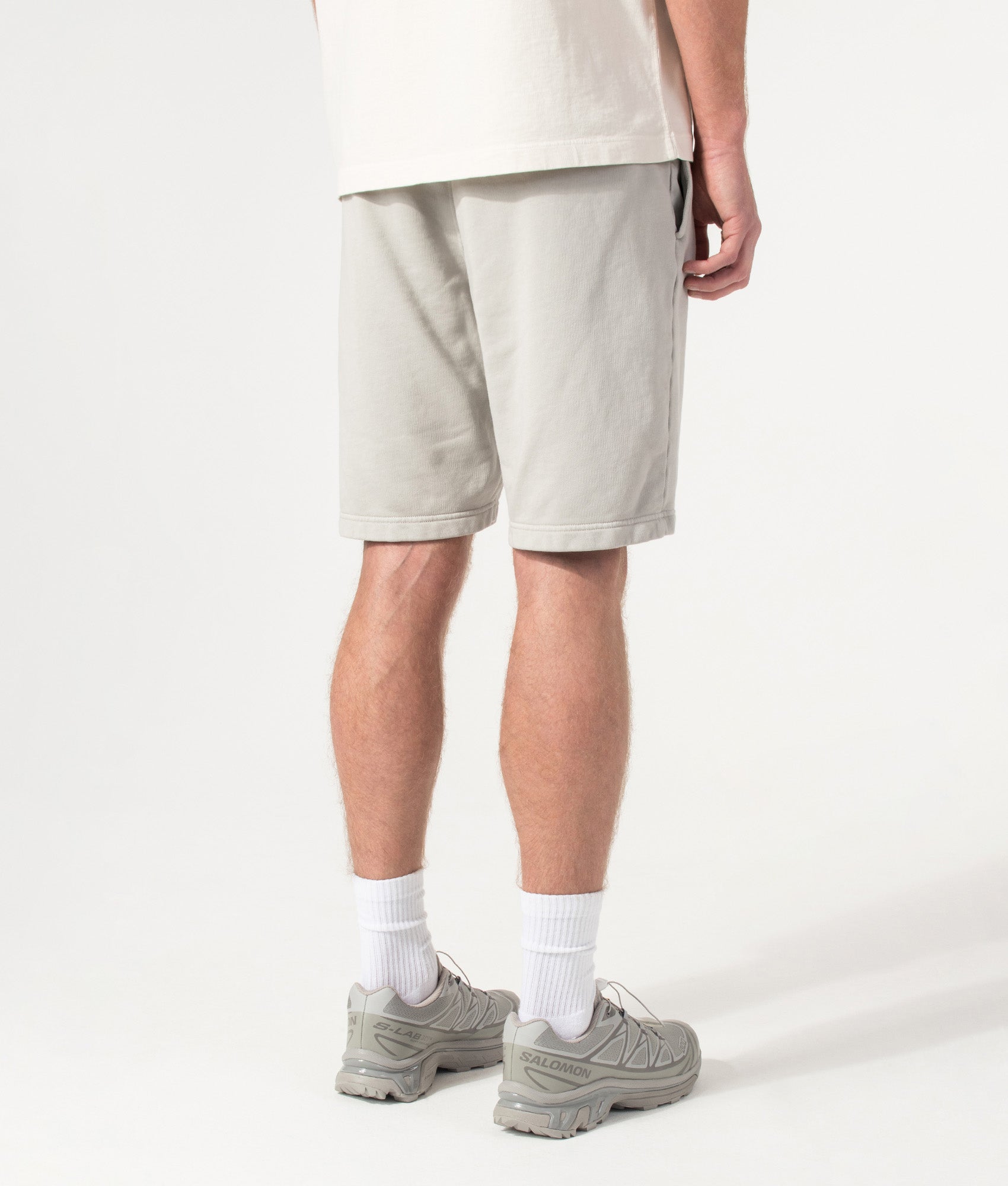 Stone Island Sweat Shorts in Pearl Grey at EQVVS Menswear. Angled model back shot.