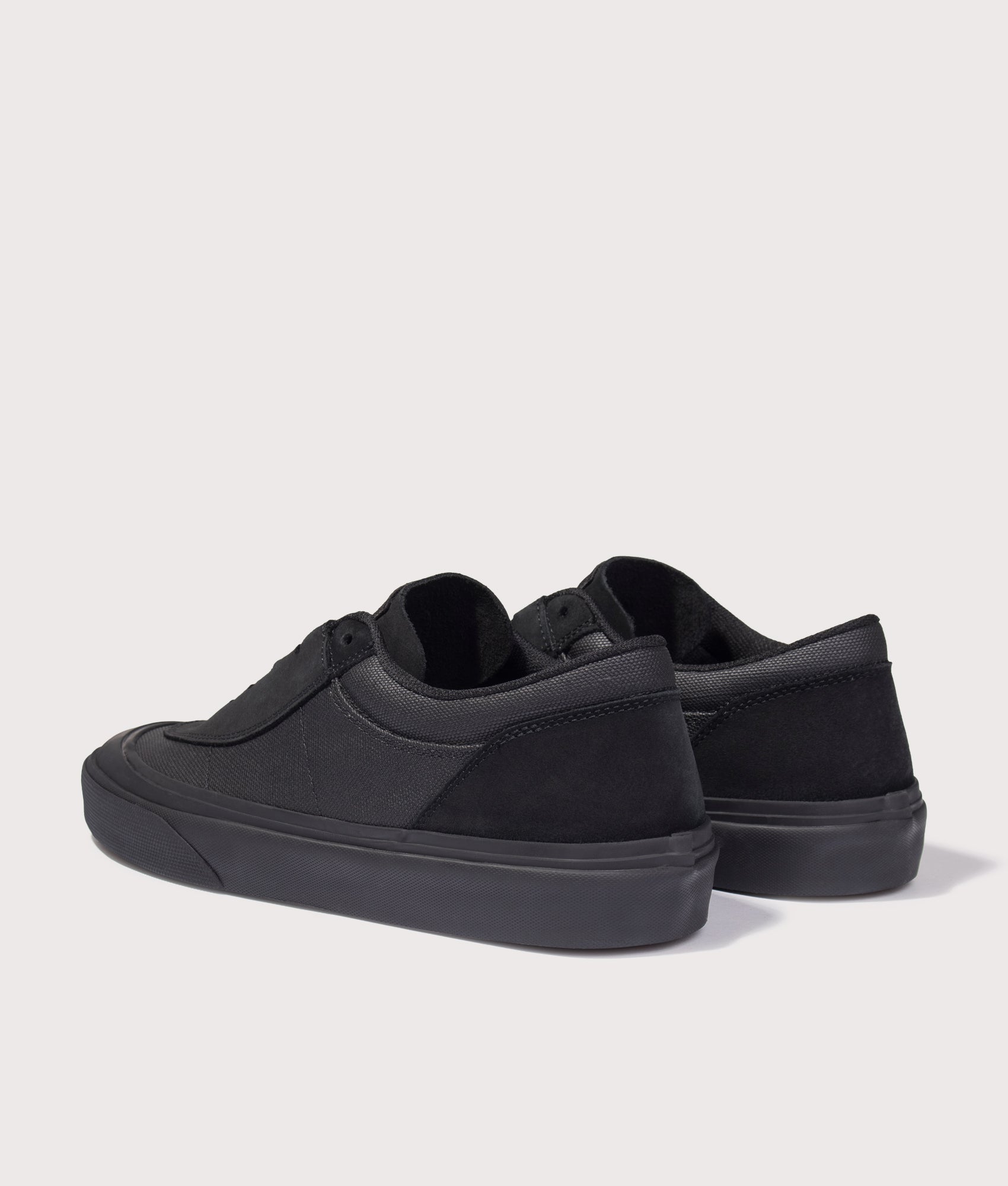Stone Island Canvas Suede Low Top Trainers in Black at EQVVS Menswear. Angled back shot.