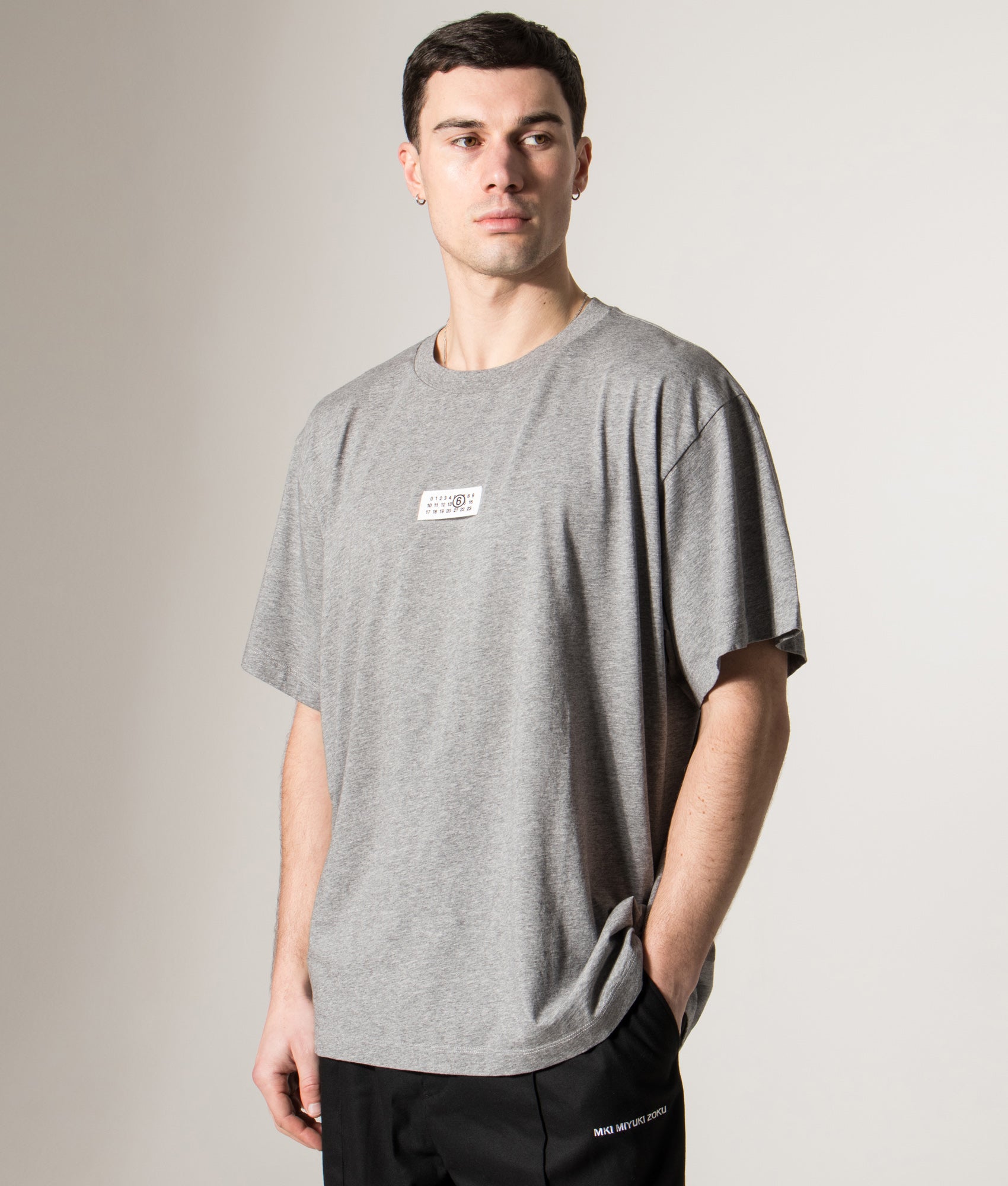 MM6 Maison Margiela Numeric Cotton T-Shirt in Light Grey Melange at EQVVS Menswear. Angled model front shot.