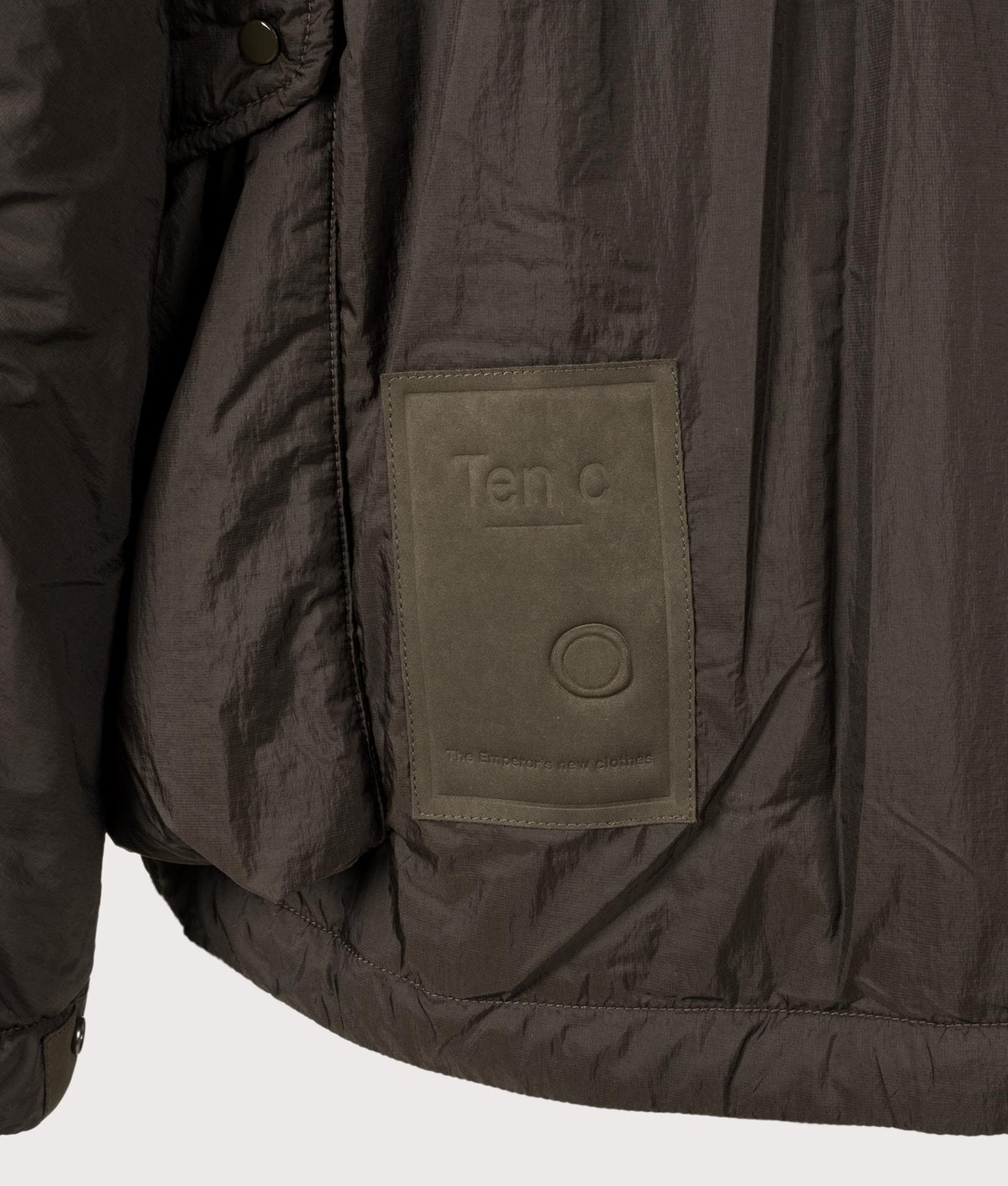 Lightly Padded Skye Ten Anorak Jacket by Ten c in Green Lizard. Shot by EQVVS. Badge detail shot.