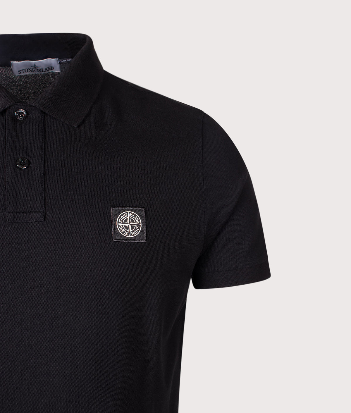 Stone Island Slim Fit Organic Cotton Piqué Polo Shirt in Black at EQVVS Menswear. Detail shot.