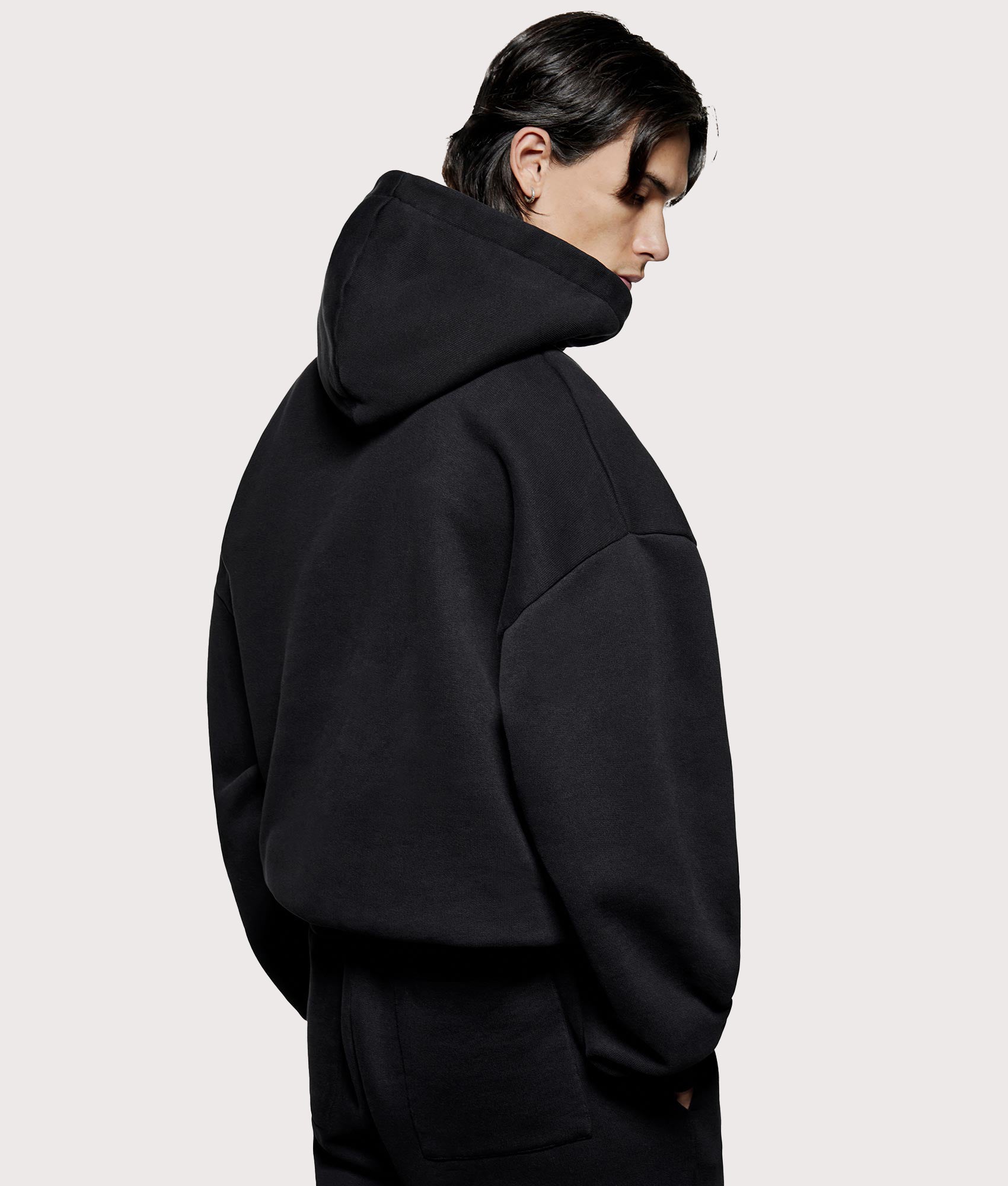 MKI MIYUKI ZOKU Oversized Uniform Hoodie in black at EQVVS Menswear. Model angled back shot.