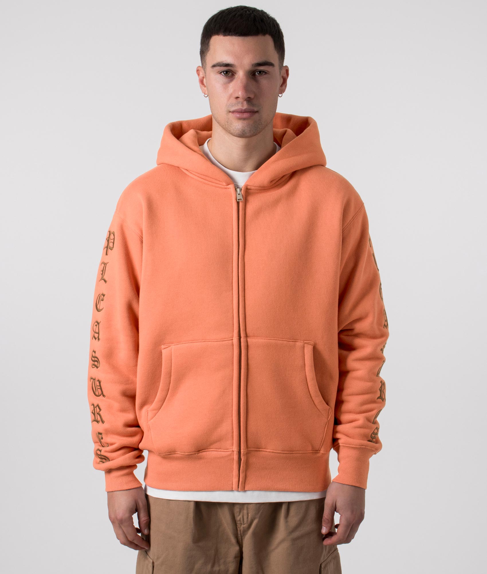 PLEASURES Relaxed Fit Old English Zip Up Hoodie in Rust, 100% Cotton. At EQVVS Menswear. Front model shot