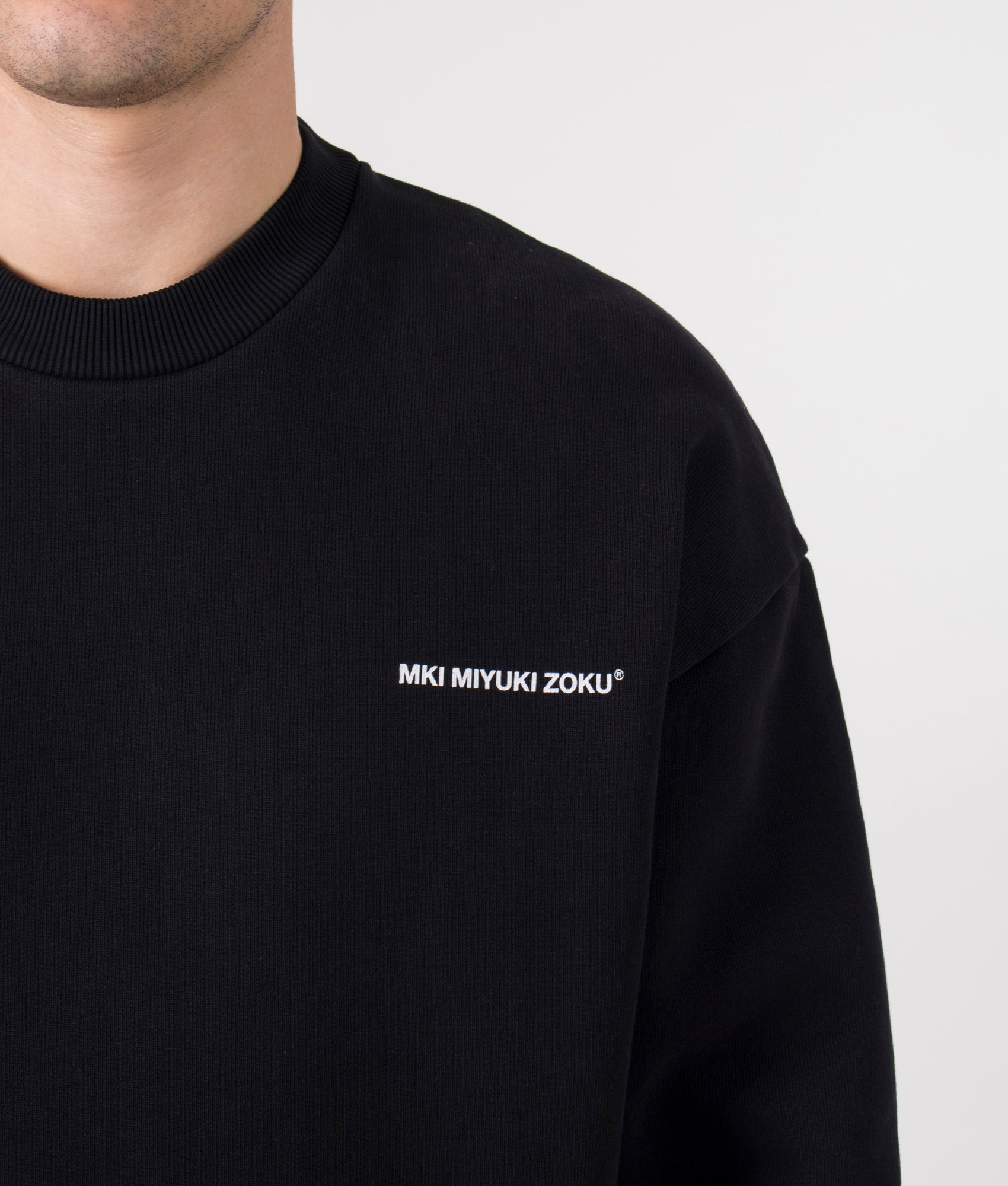 MKI MIYUKI ZOKU Oversized Uniform Crewneck Sweatshirt in Black at EQVVS Menswear. Model detail shot.