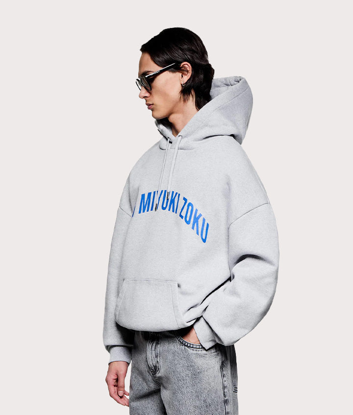 MKI MIYUKI ZOKU Oversized Arch Hoodie in Grey at EQVVS Menswear. Angled model front shot.