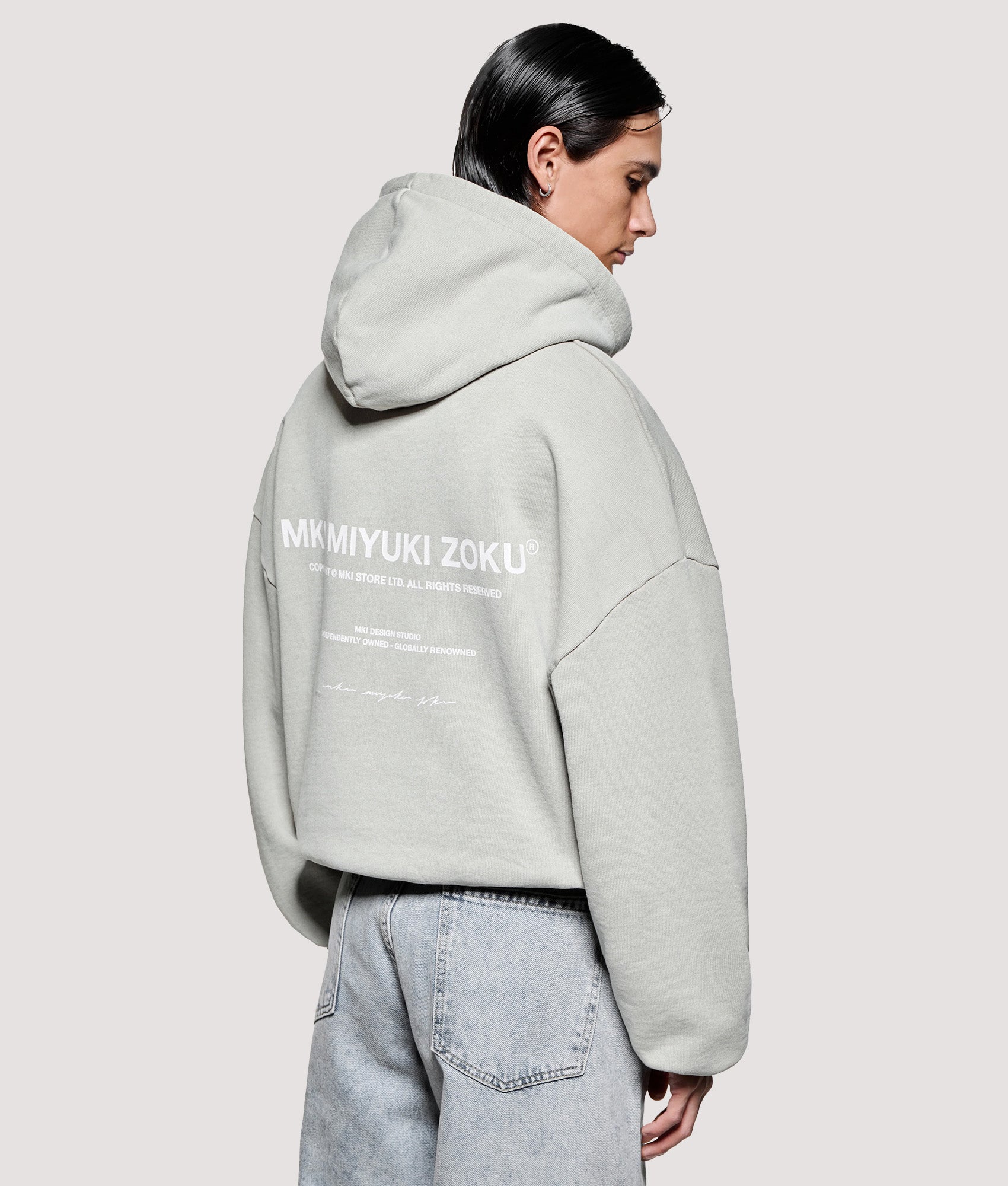 MKI MIYUKI ZOKU Box Fit Design Studio Hoodie in Pigment Cement at EQVVS Menswear. Angled model back shot.