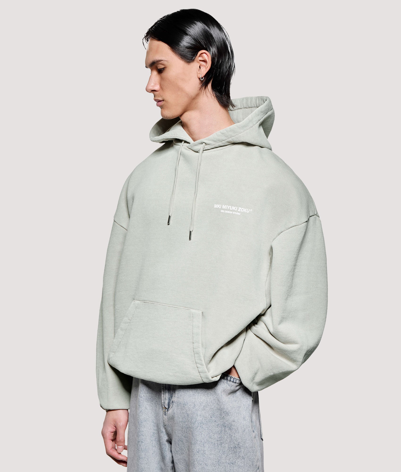 MKI MIYUKI ZOKU Box Fit Design Studio Hoodie in Pigment Cement at EQVVS Menswear. Angled model front shot.