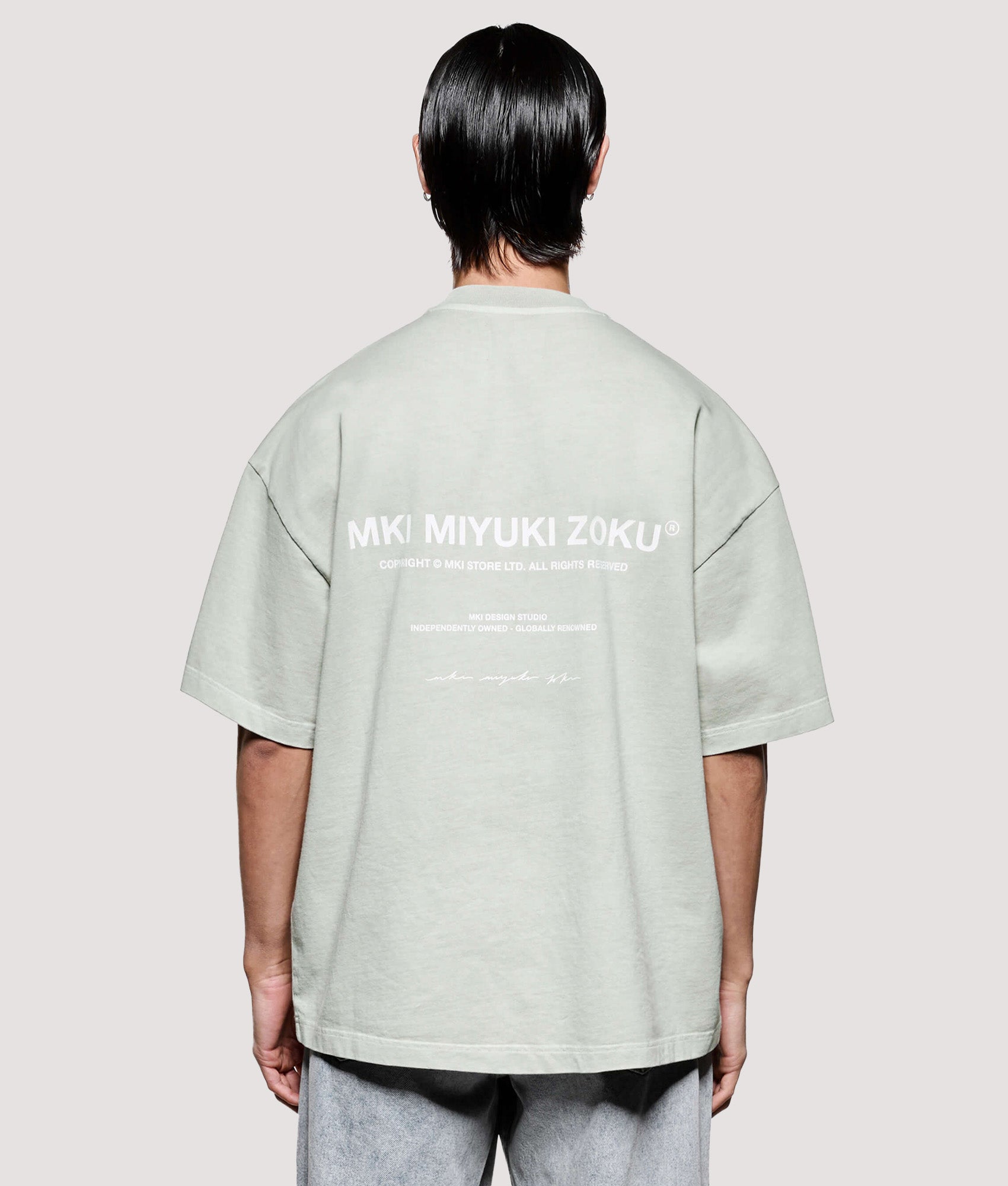 MKI MIYUKI ZOKU Box Fit Design Studio T-Shirt in Pigment Cement at EQVVS Menswear. Model back shot.