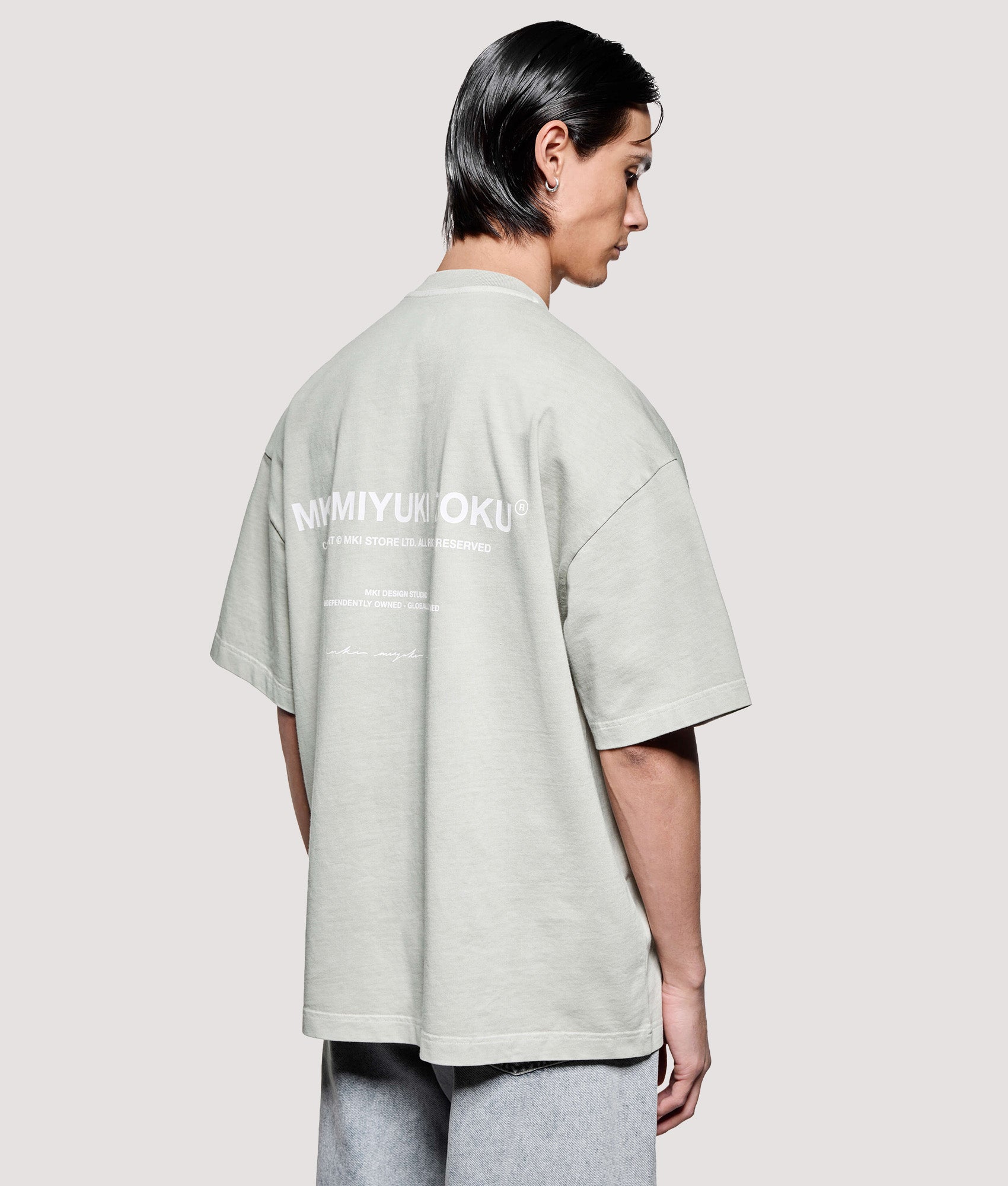 MKI MIYUKI ZOKU Box Fit Design Studio T-Shirt in Pigment Cement at EQVVS Menswear. Angled model back shot.