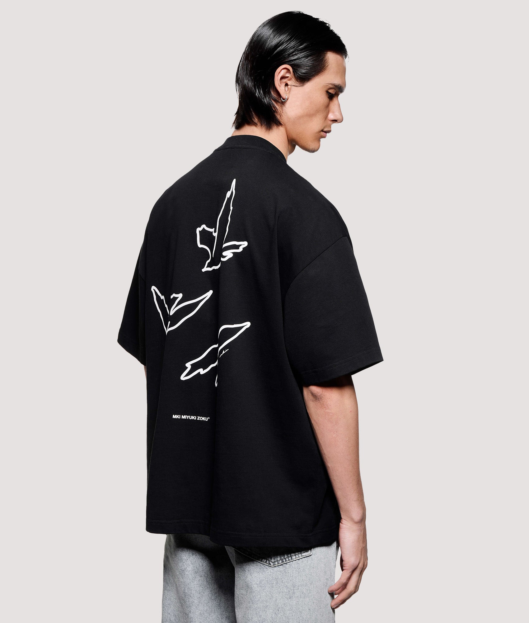 MKI MIYUKI ZOKU Box Fit Flight T-Shirt in Black at EQVVS Menswear. Angled model back shot.