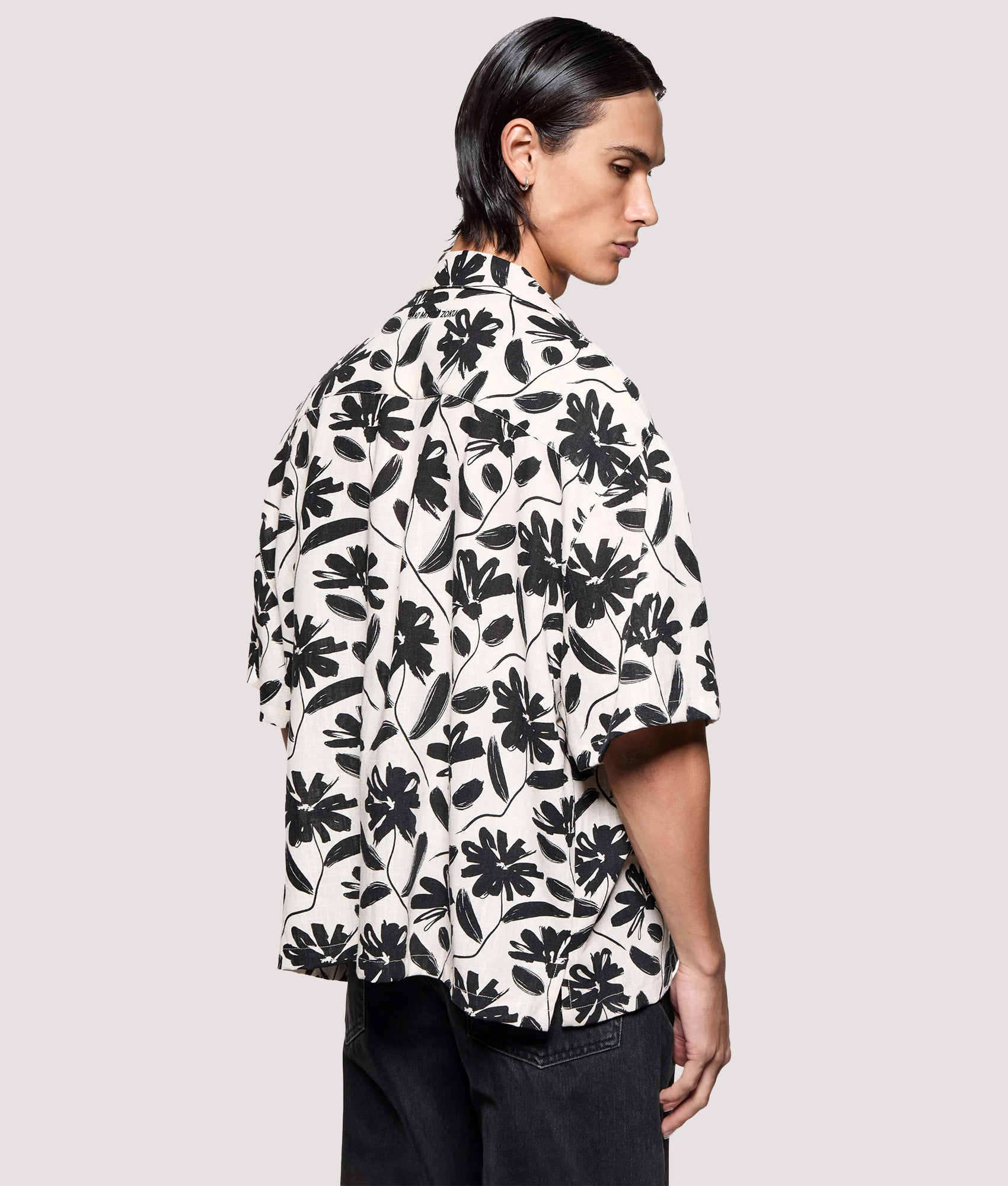 MKI MIYUKI ZOKU Box Fit Floral Linen Short Sleeve Vacation Shirt in Raw at EQVVS Menswear. Angled model back shot.