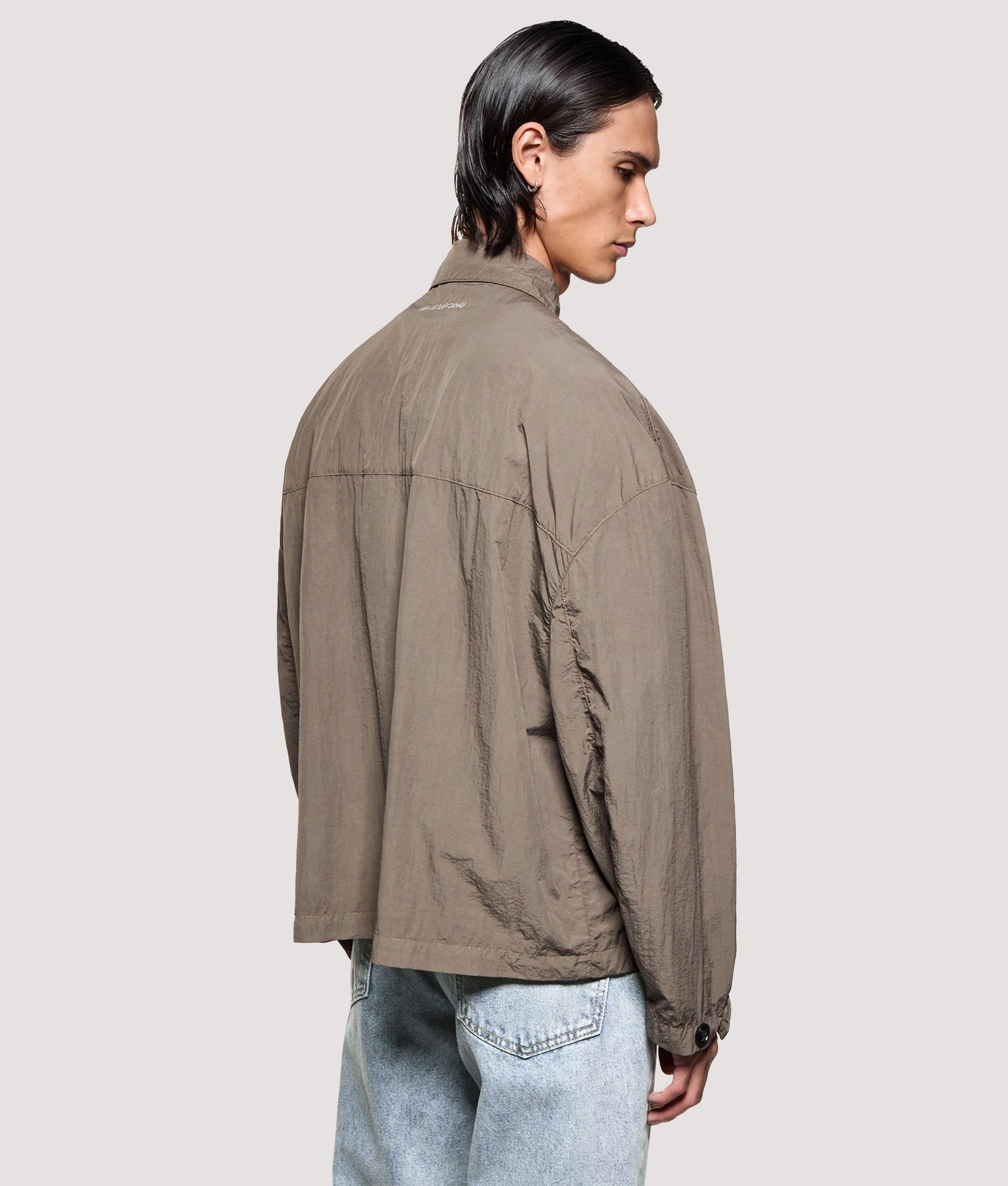 MKI MIYUKI ZOKU Box Fit Garment Dye Overshirt in Deep Khaki at EQVVS Menswear. Angled model back shot.