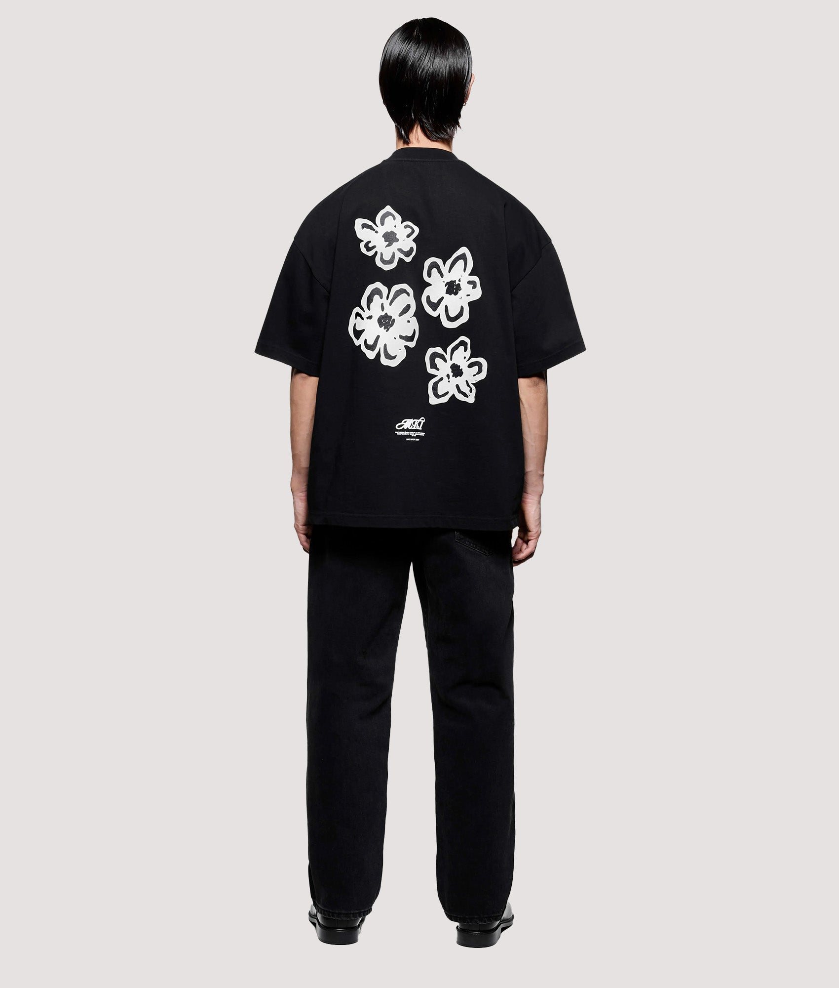 MKI MIYUKI ZOKU Box Fit Hibiscus T-Shirt in Black at EQVVS Menswear. Model full back shot.