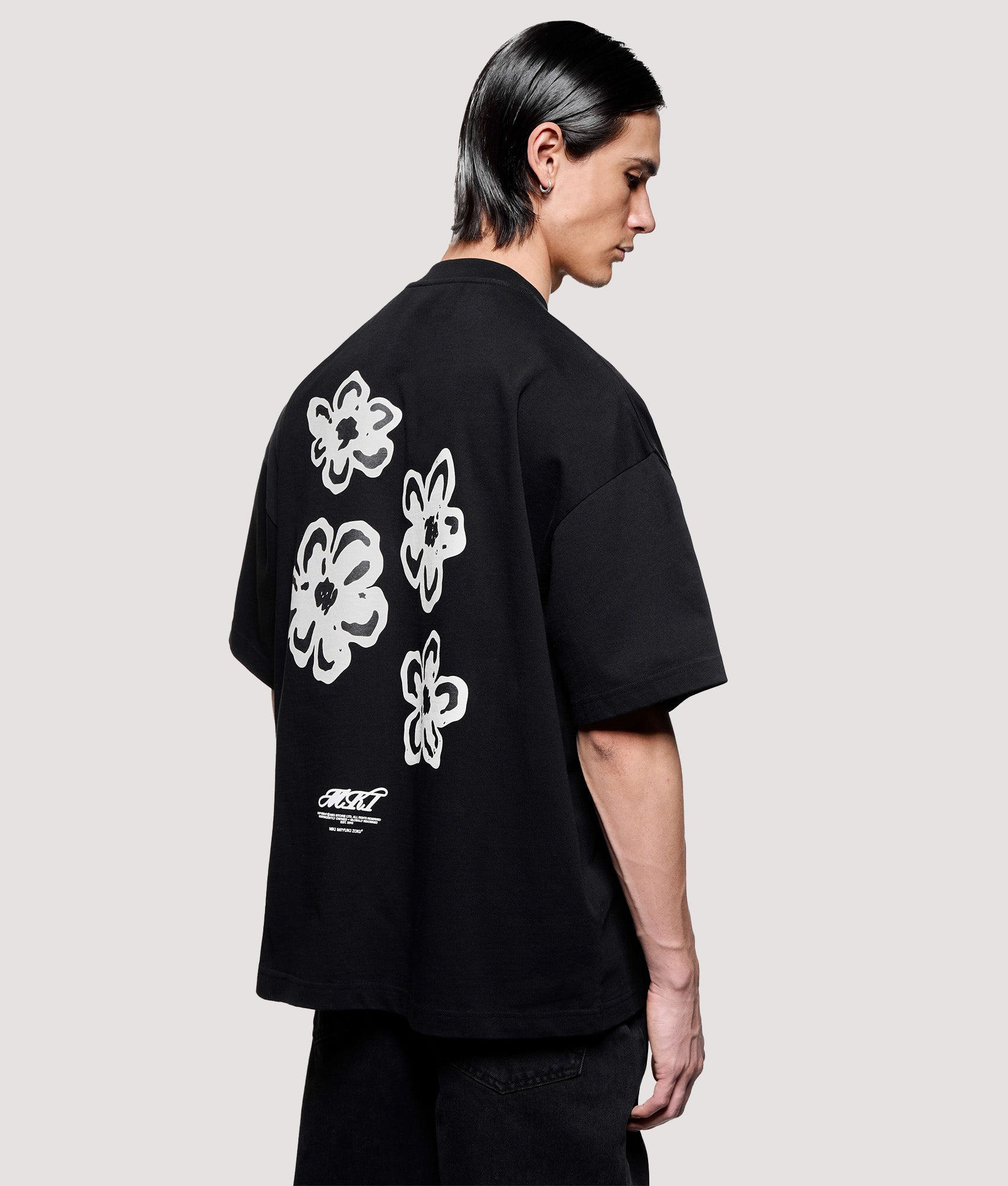 MKI MIYUKI ZOKU Box Fit Hibiscus T-Shirt in Black at EQVVS Menswear. Angled model back shot.