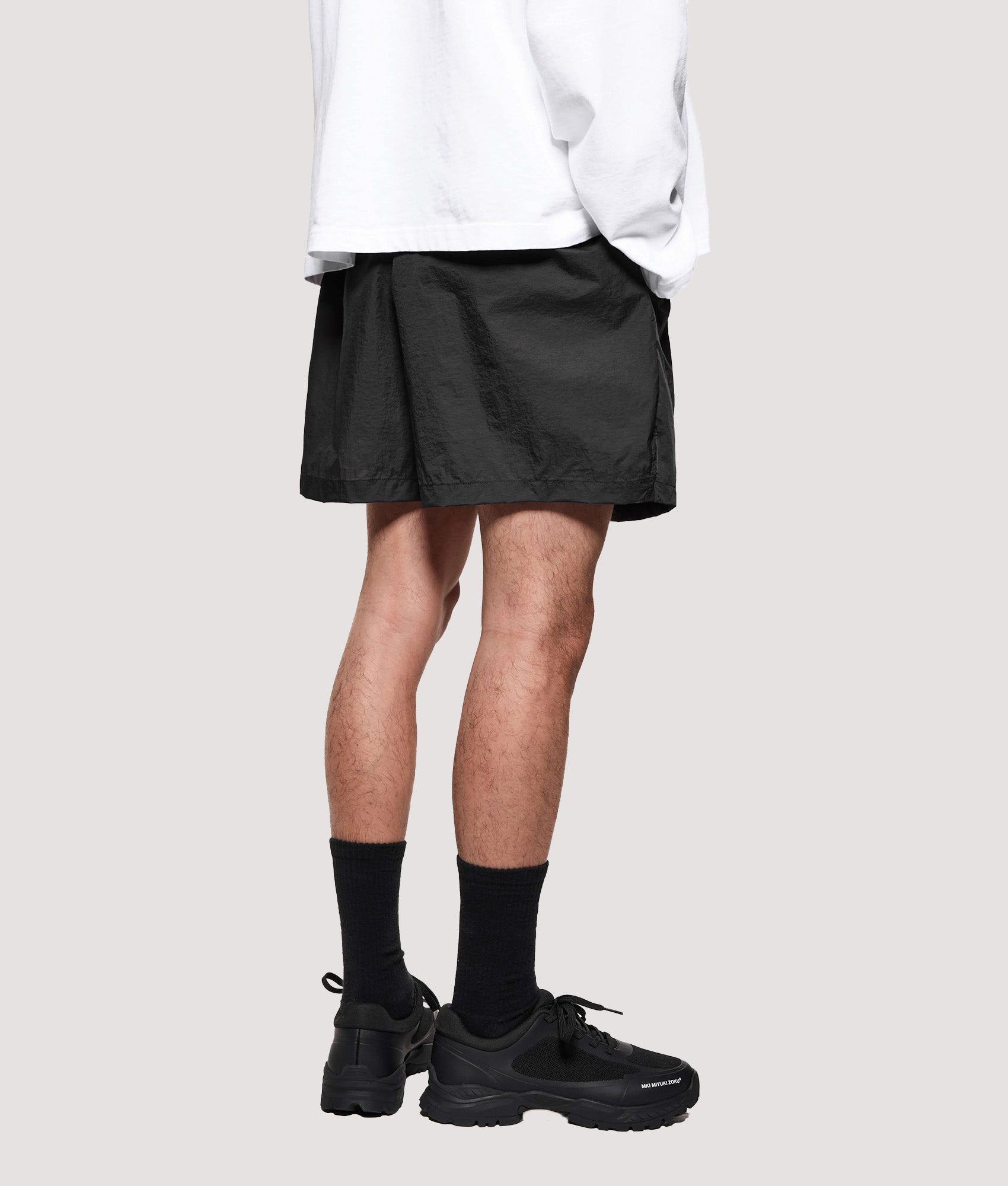 MKI MIYUKI ZOKU Relaxed Fit Hyperlight Wind Shorts in Black at EQVVS Menswear. Model back shot.