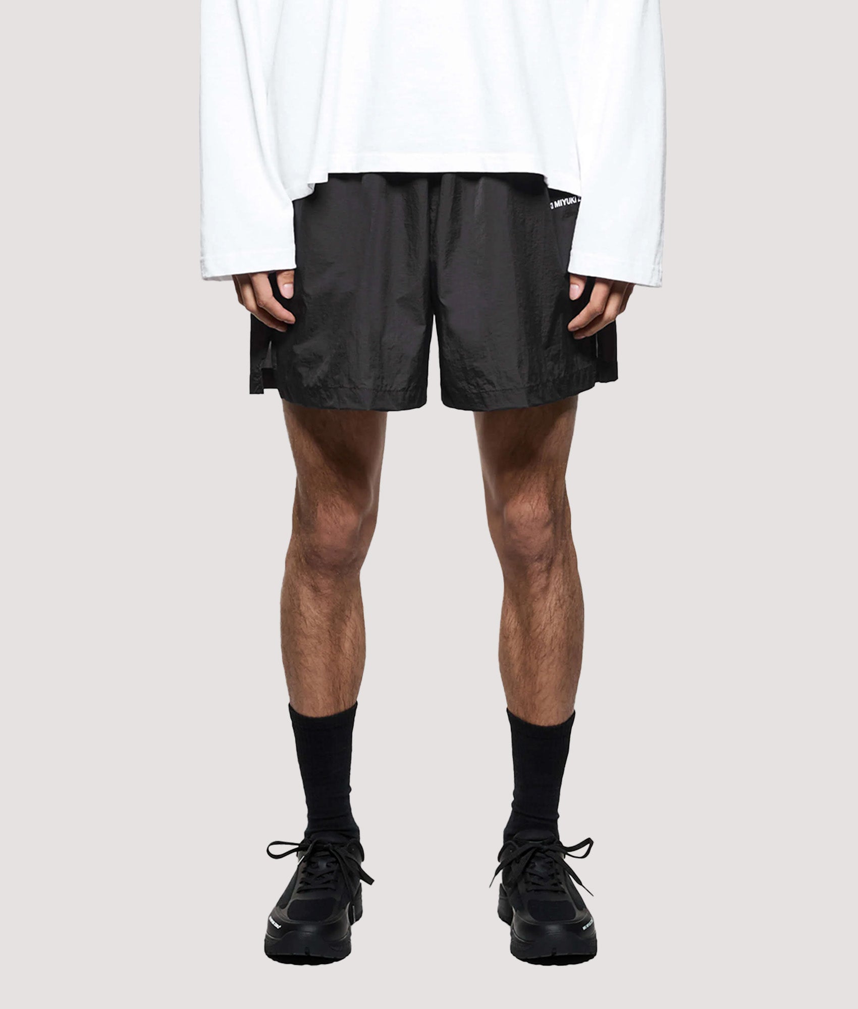 MKI MIYUKI ZOKU Relaxed Fit Hyperlight Wind Shorts in Black at EQVVS Menswear. Model front shot.