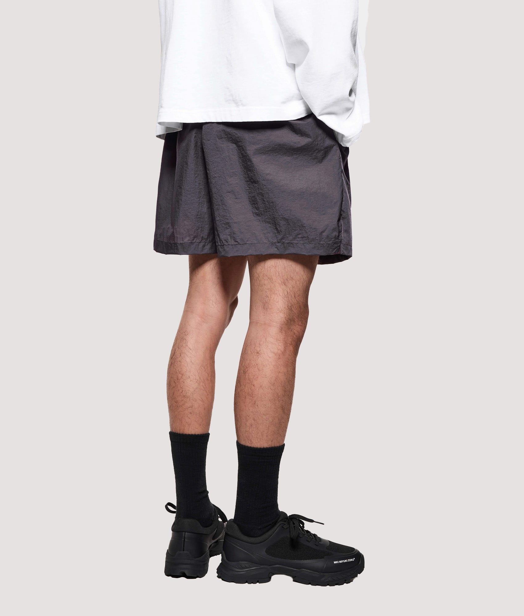 MKI MIYUKI ZOKU Relaxed Fit Hyperlight Wind Shorts in Raisin at EQVVS Menswear. Angled model back shot.