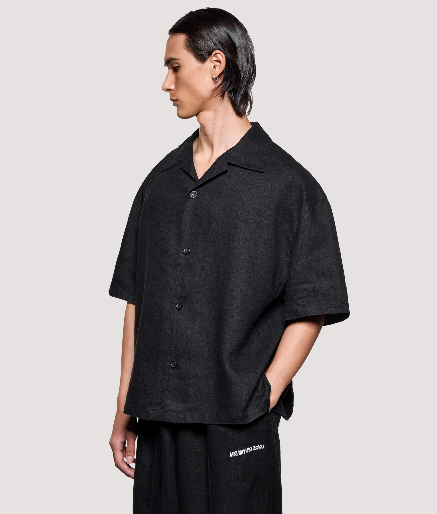 MKI MIYUKI ZOKU Box Fit Linen Short Sleeve Vacation Shirt in Black at EQVVS Menswear. Angled model front shot.