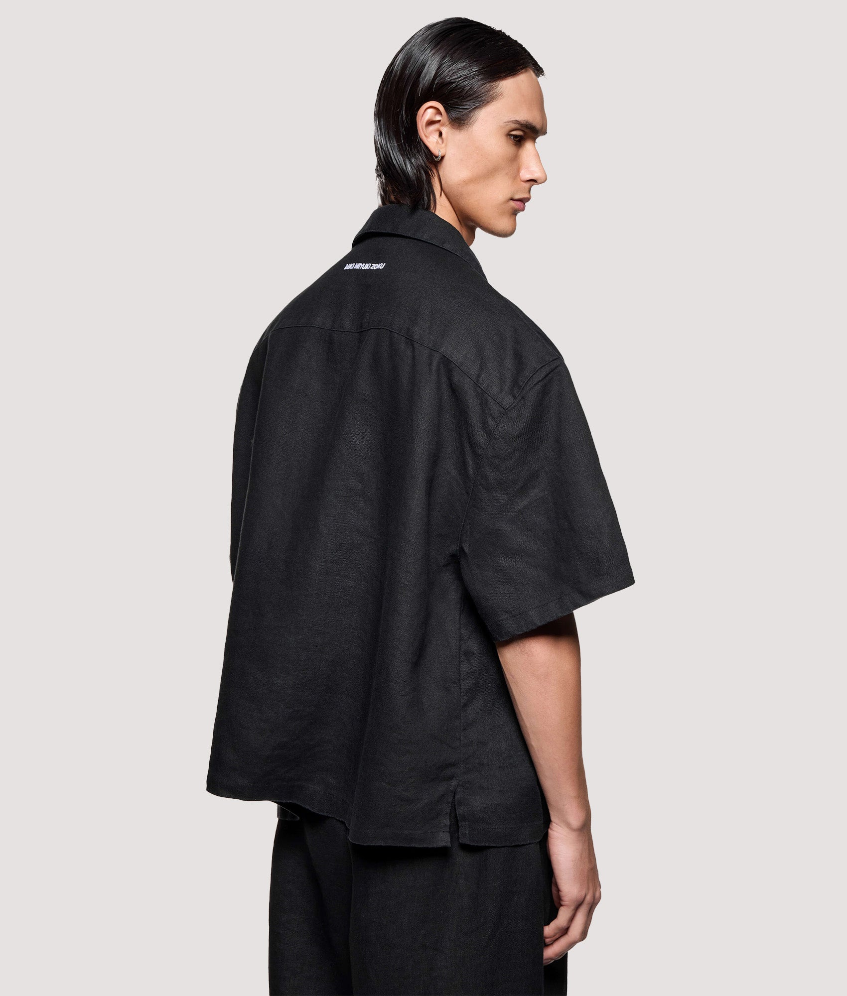 MKI MIYUKI ZOKU Box Fit Linen Short Sleeve Vacation Shirt in Black at EQVVS Menswear. Angled model back shot.
