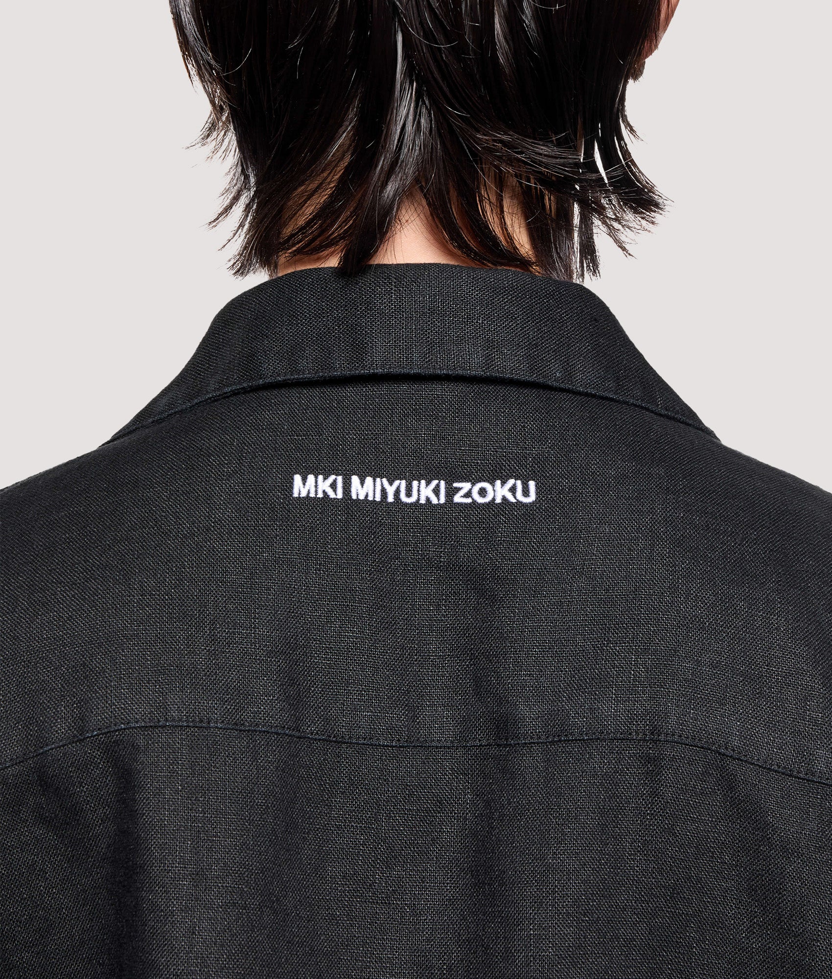 MKI MIYUKI ZOKU Box Fit Linen Short Sleeve Vacation Shirt in Black at EQVVS Menswear. Back detail shot.