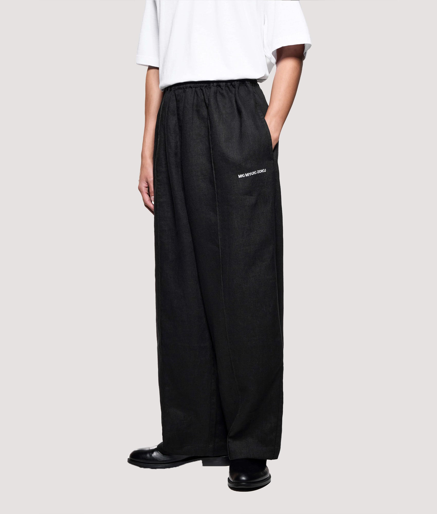 MKI MIYUKI ZOKU Relaxed Fit Linen Wide Leg Pants in Black at EQVVS Menswear. Angled model front shot.