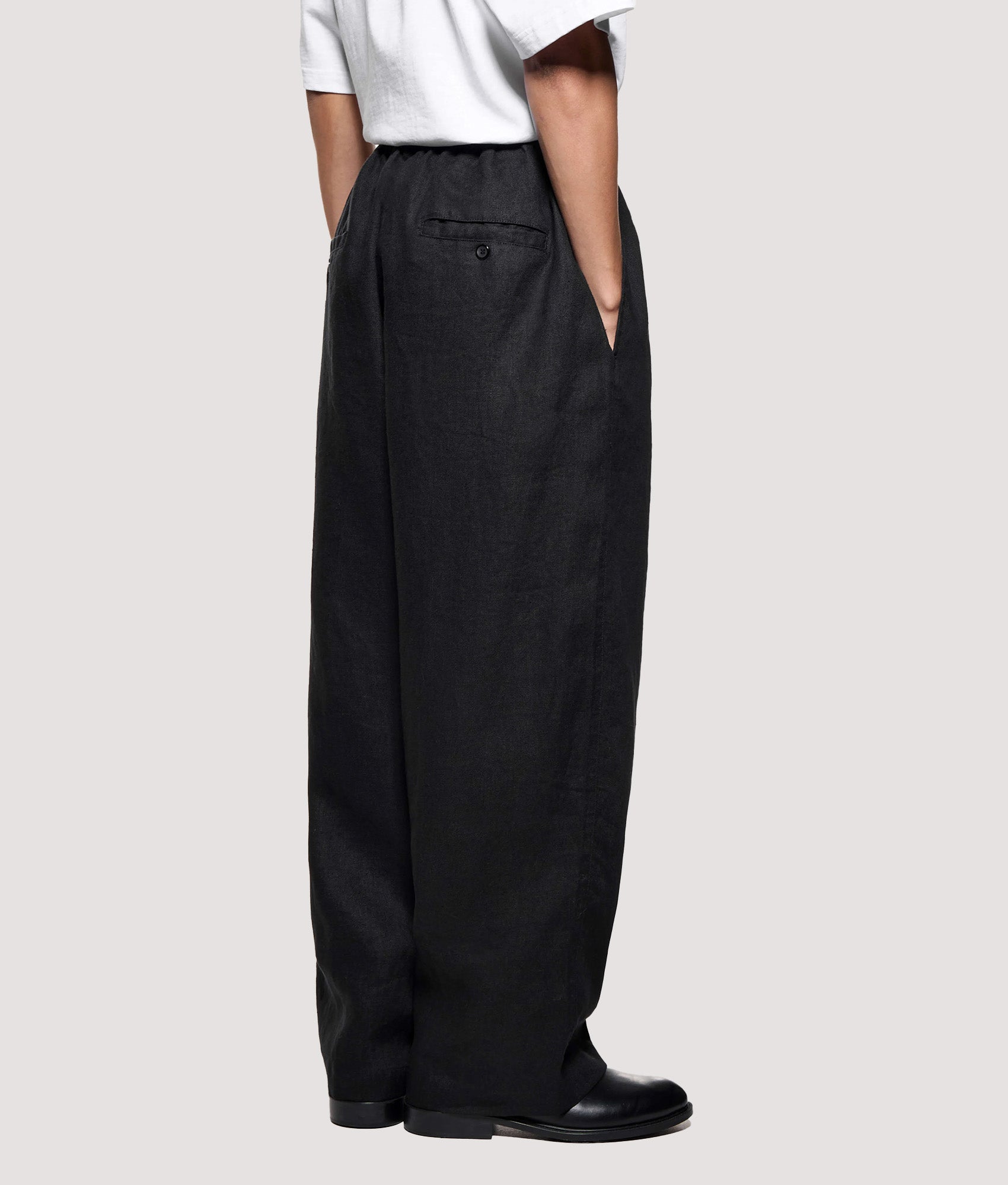 MKI MIYUKI ZOKU Relaxed Fit Linen Wide Leg Pants in Black at EQVVS Menswear. Angled model back shot.
