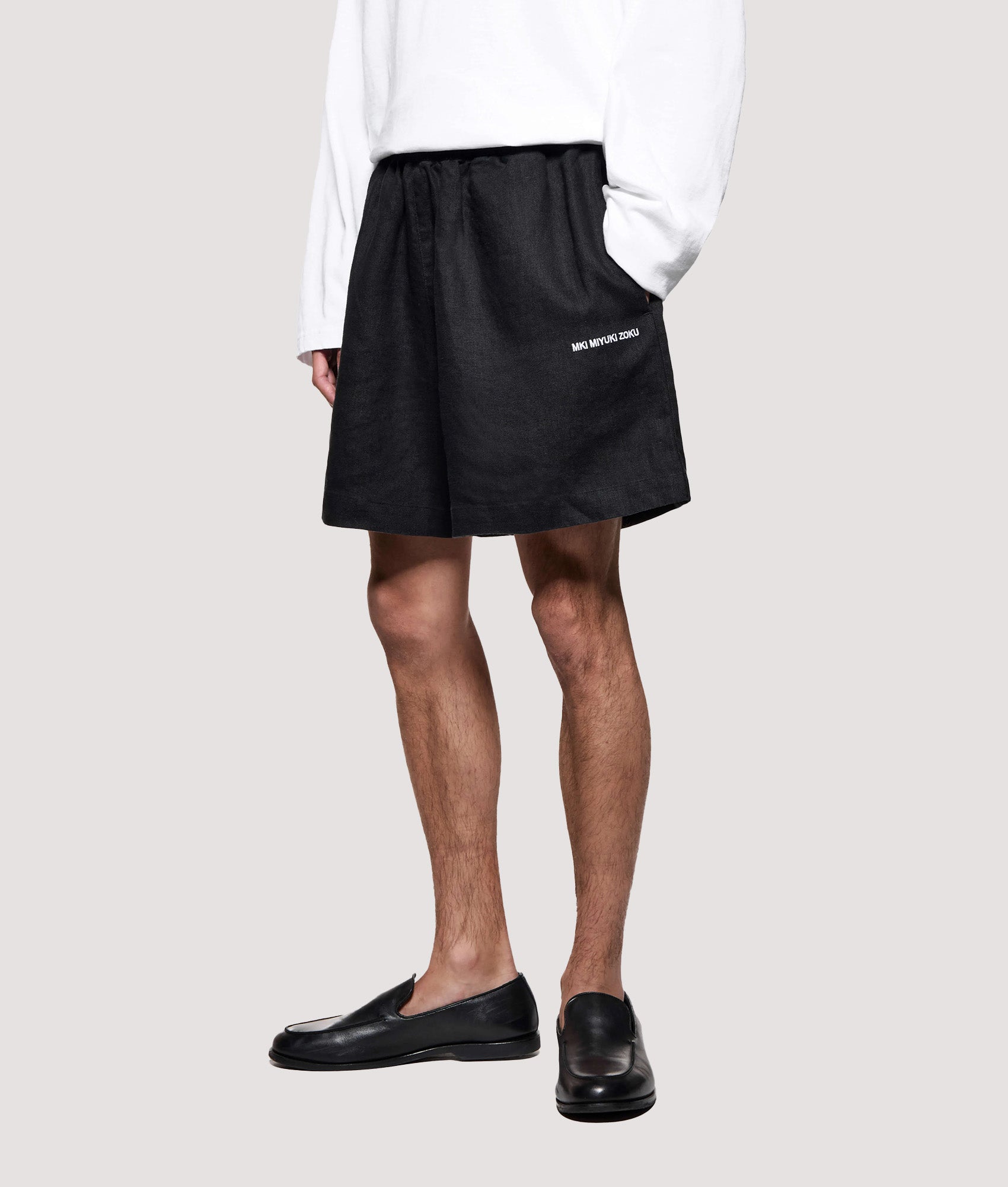 MKI MIYUKI ZOKU Relaxed Fit Linen Wide Leg Shorts in Black at EQVVS Menswear. Model front shot.