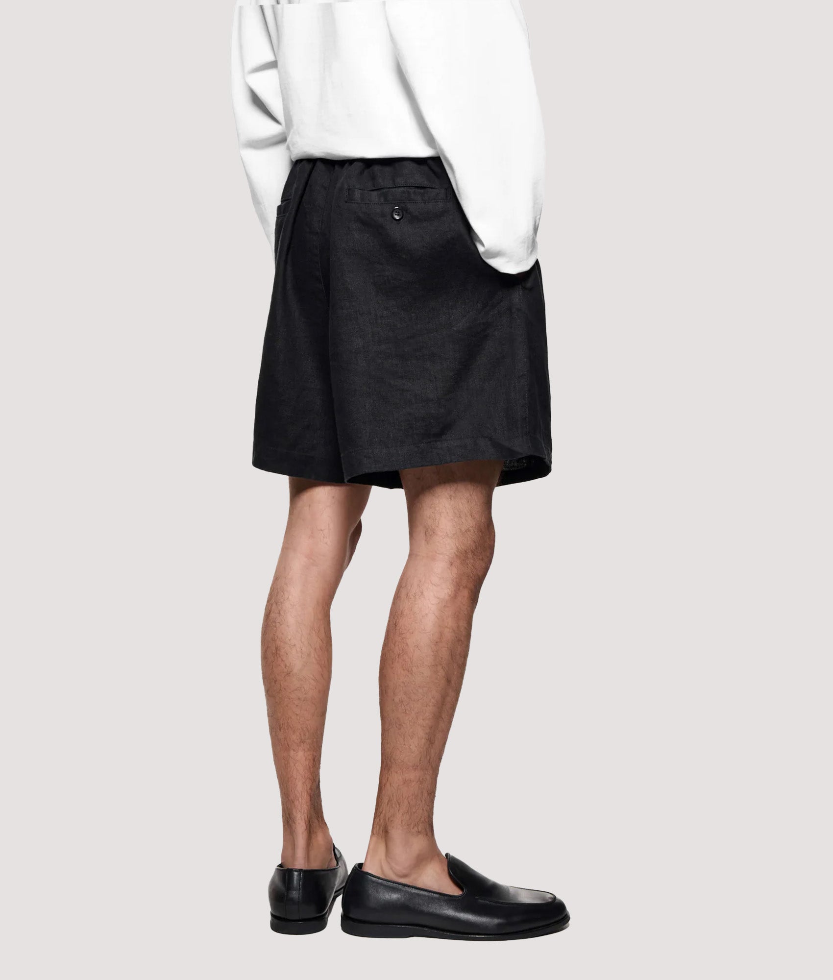 MKI MIYUKI ZOKU Relaxed Fit Linen Wide Leg Shorts in Black at EQVVS Menswear. Model back shot.