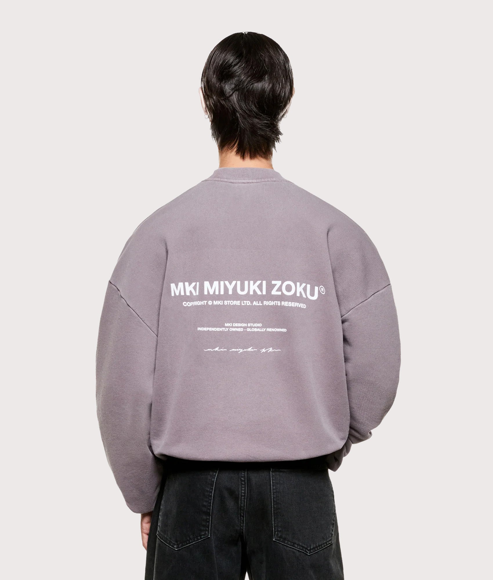 MKI MIYUKI ZOKU Oversized Design Studio Crewneck Sweatshirt in Pigment Raisin. Model back shot.