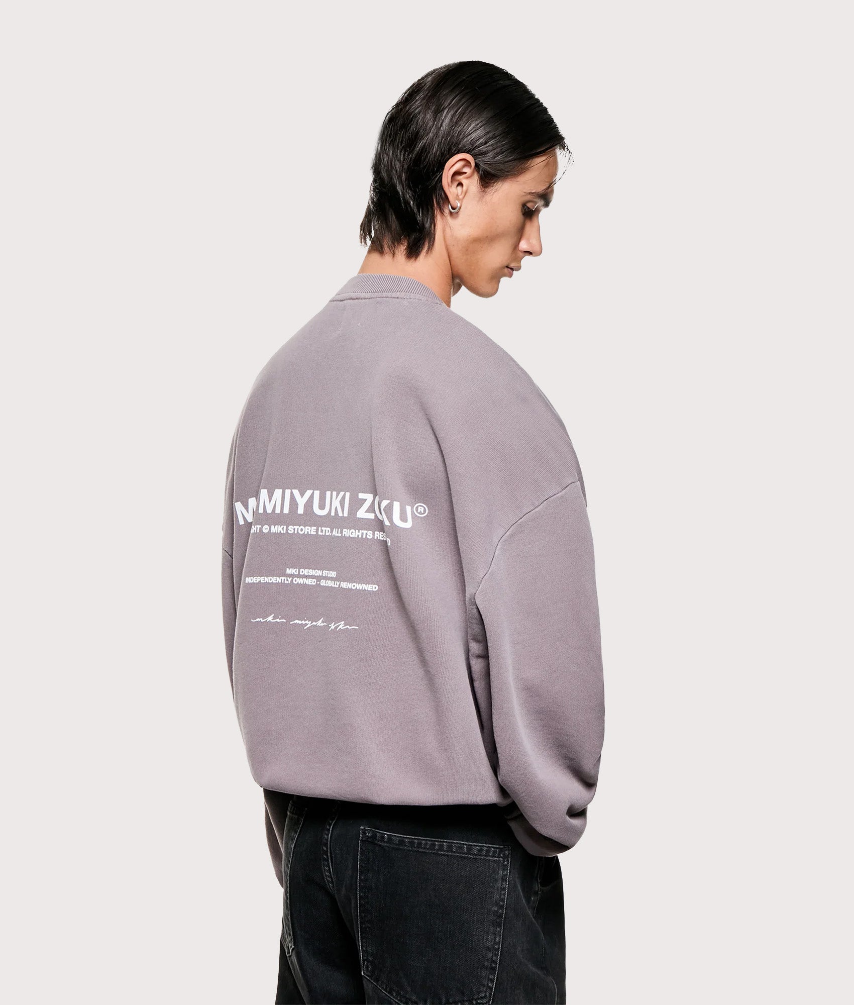 MKI MIYUKI ZOKU Oversized Design Studio Crewneck Sweatshirt in Pigment Raisin. Angled model back shot.