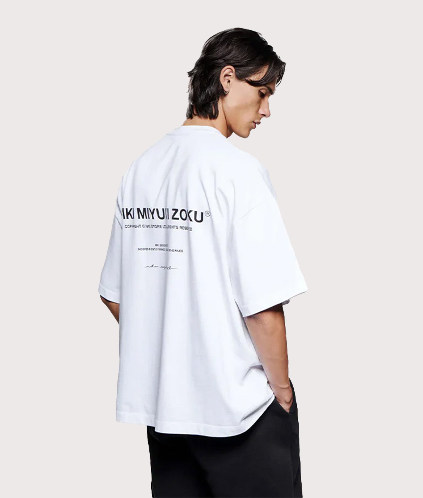 MKI MIYUKI ZOKU Oversized Fit Design Studio T-Shirt in White at EQVVS Menswear. Model back shot.