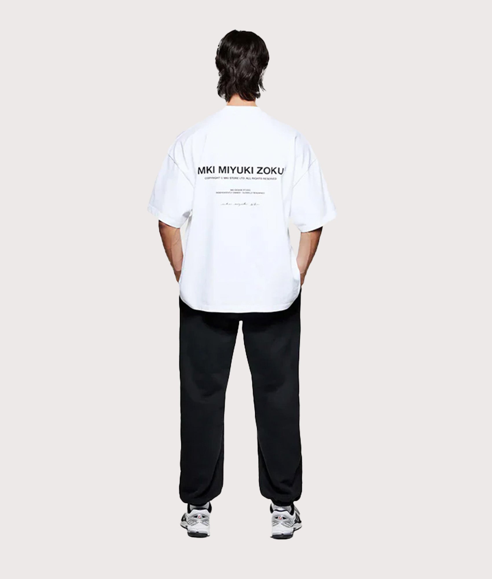 MKI MIYUKI ZOKU Oversized Fit Design Studio T-Shirt in White at EQVVS Menswear. Model full back shot.