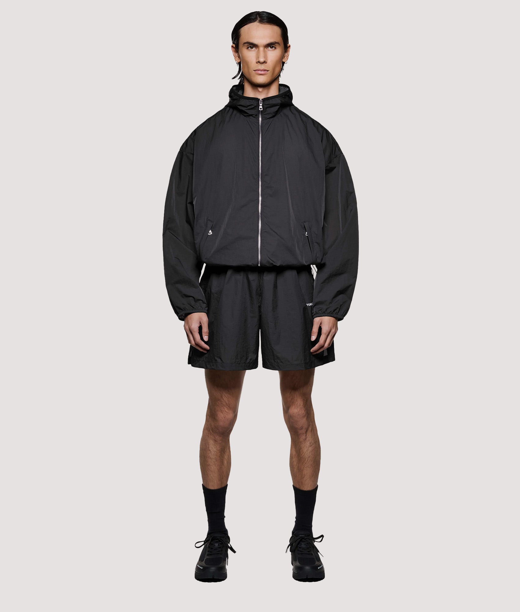 MKI MIYUKI ZOKU Box Fit Hyperlight Hooded Wind Jacket in Black at EQVVS Menswear. Model full front shot.