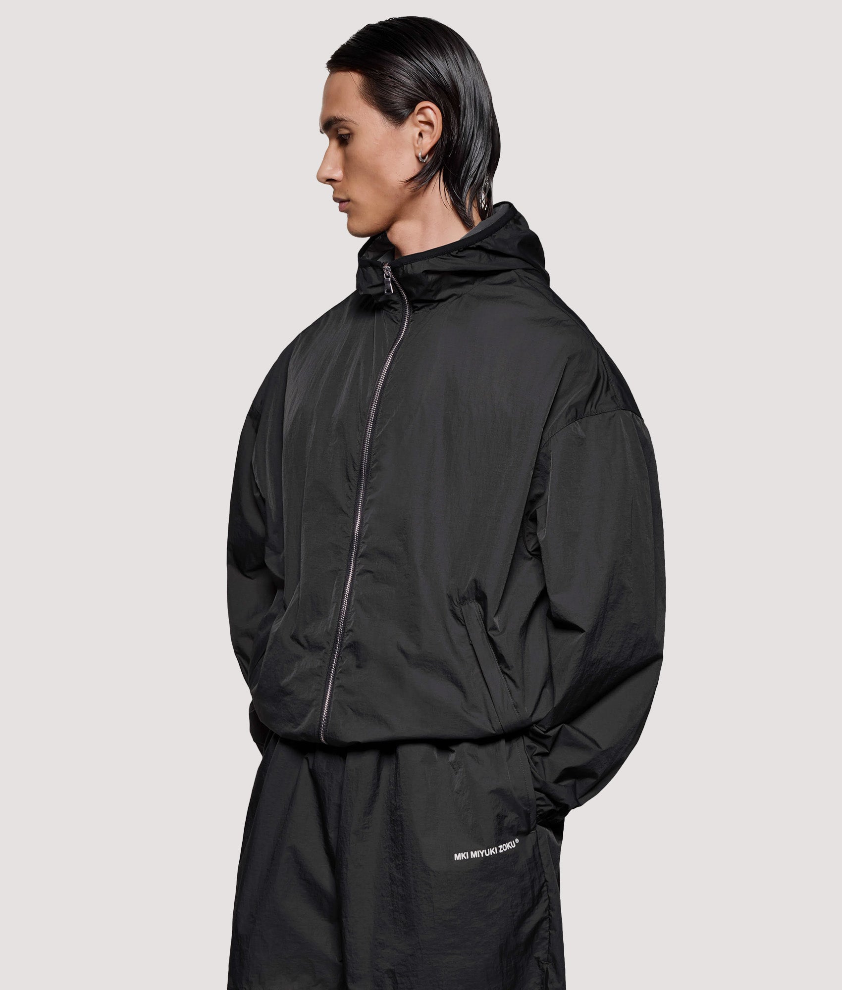 MKI MIYUKI ZOKU Box Fit Hyperlight Hooded Wind Jacket in Black at EQVVS Menswear. Angled model front shot.