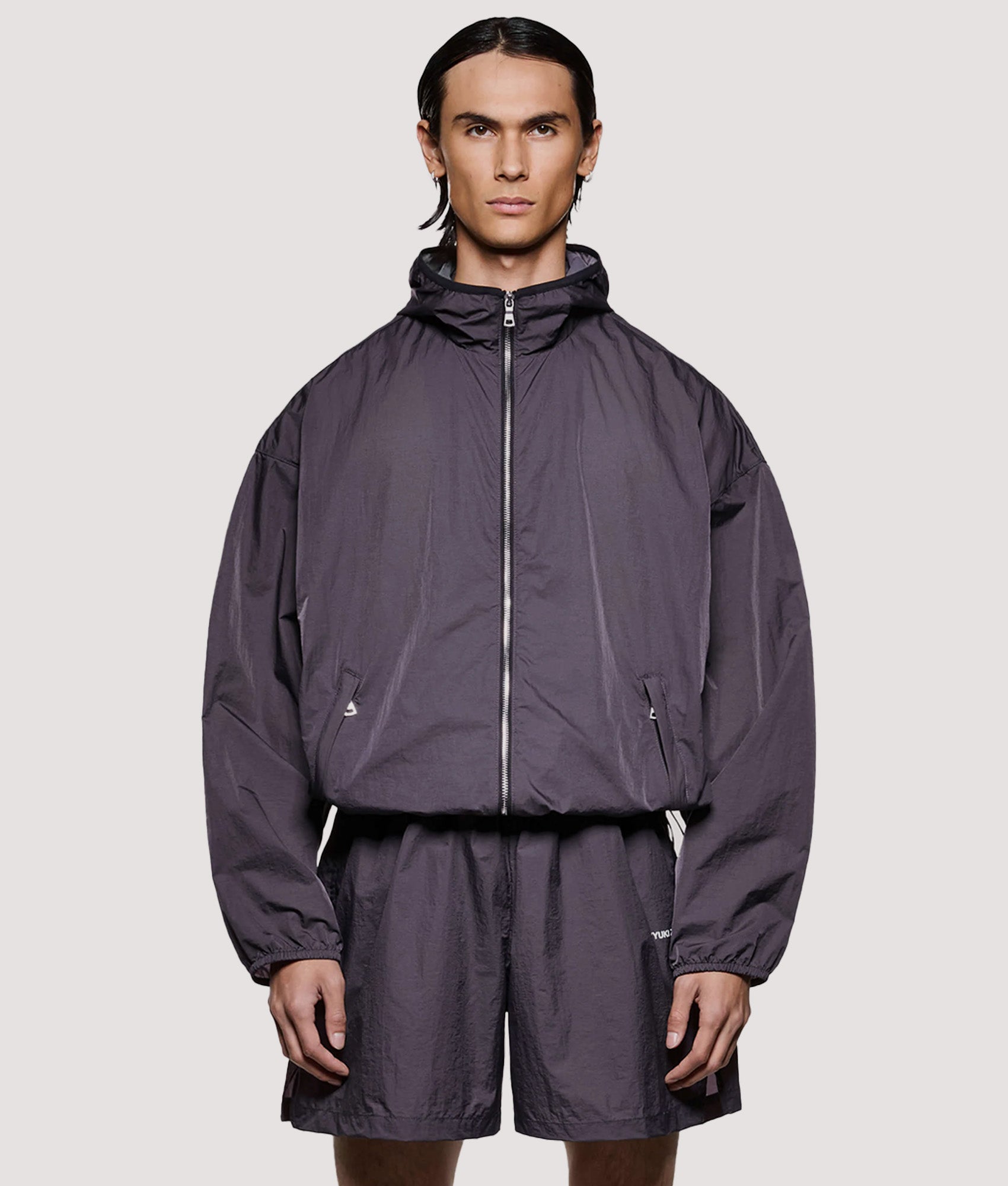 MKI MIYUKI ZOKU Box Fit Hyperlight Hooded Wind Jacket in Raisin at EQVVS Menswear. Model front shot.