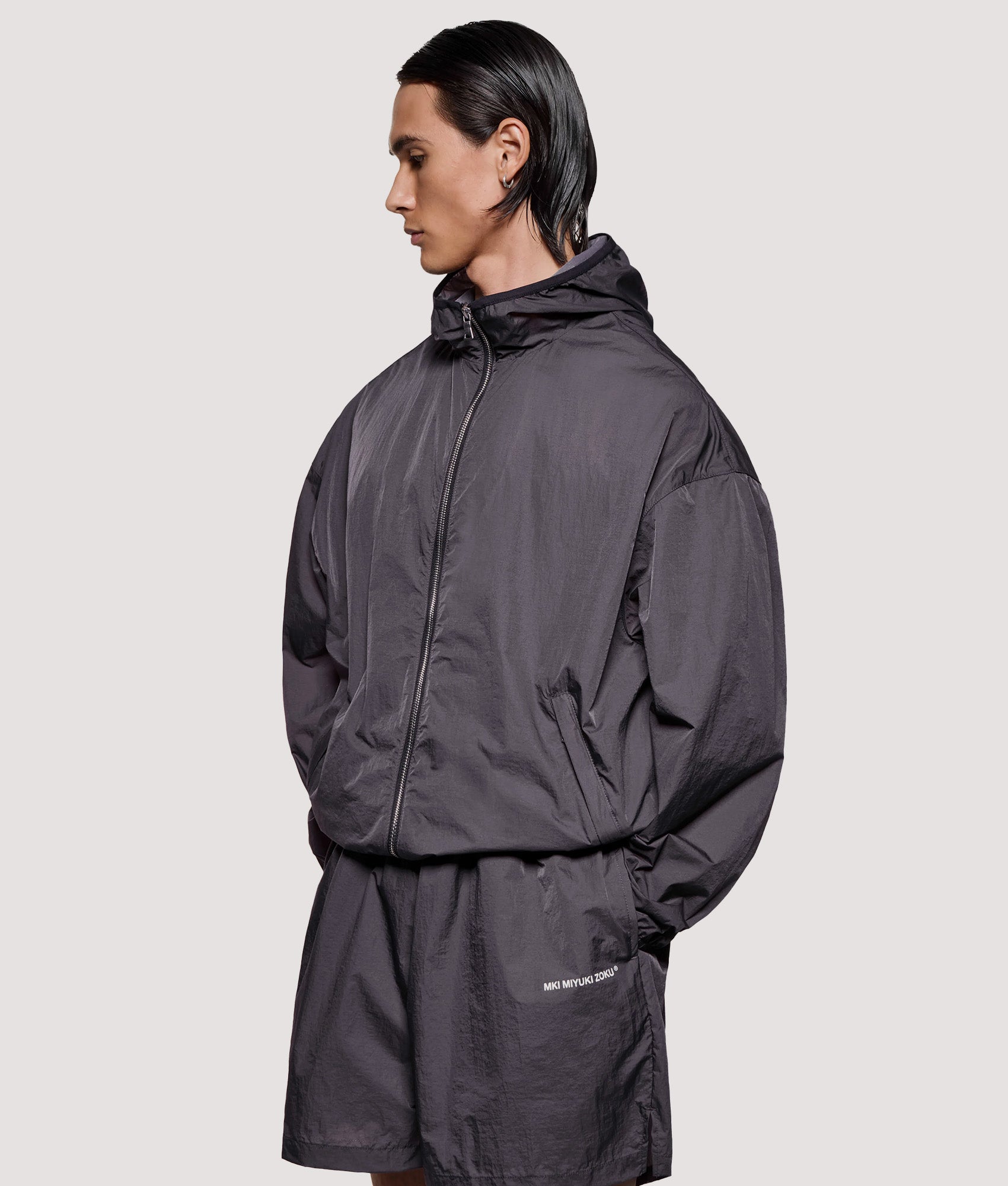 MKI MIYUKI ZOKU Box Fit Hyperlight Hooded Wind Jacket in Raisin at EQVVS Menswear. Angled model front shot.