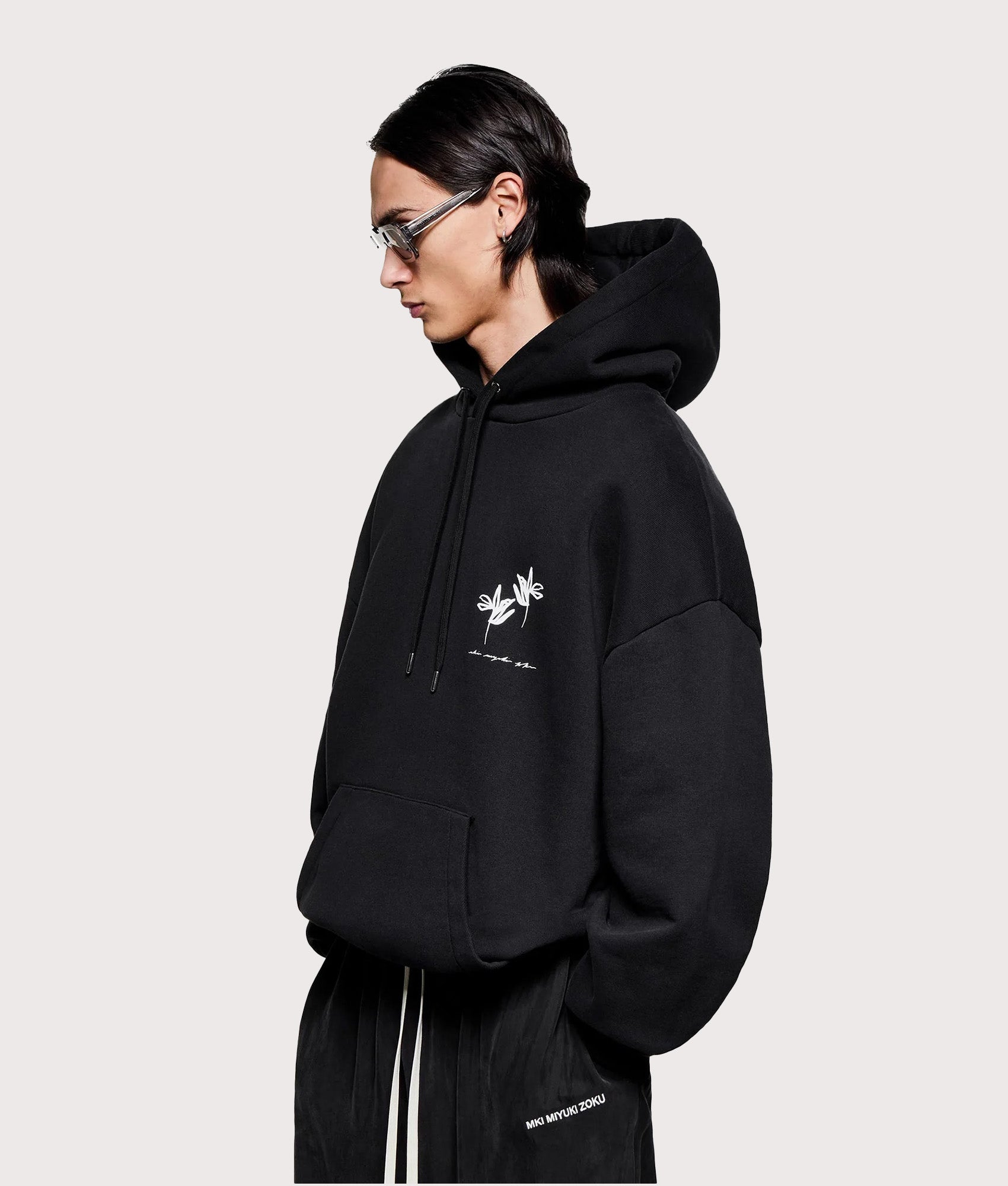 MKI MIYUKI ZOKU Relaxed Fit Ink Flower Hoodie in Black at EQVVS Menswear. Angled model front shot.