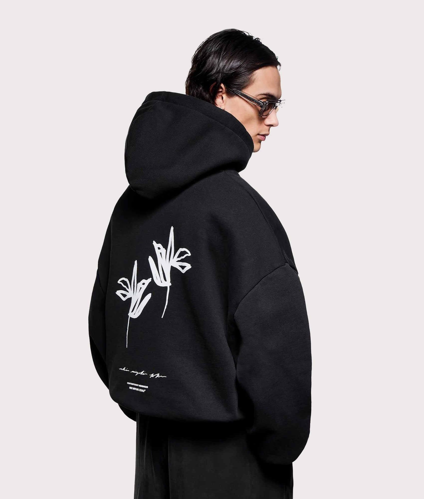 MKI MIYUKI ZOKU Relaxed Fit Ink Flower Hoodie in Black at EQVVS Menswear. Angled model Back shot.