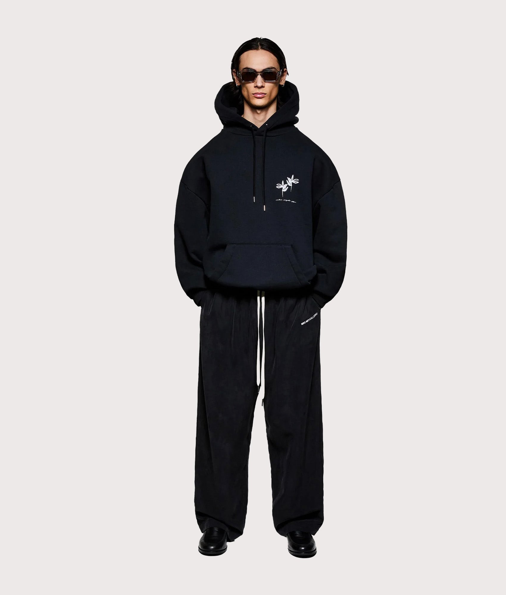 MKI MIYUKI ZOKU Relaxed Fit Ink Flower Hoodie in Black at EQVVS Menswear. Model full front. 