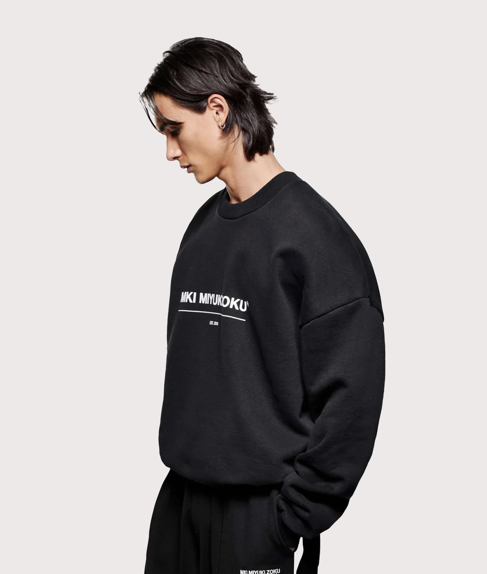 MKI MIYUKI ZOKU Oversized Linear Crewneck Sweatshirt in Black at EQVVS Menswear. Angled model shot.