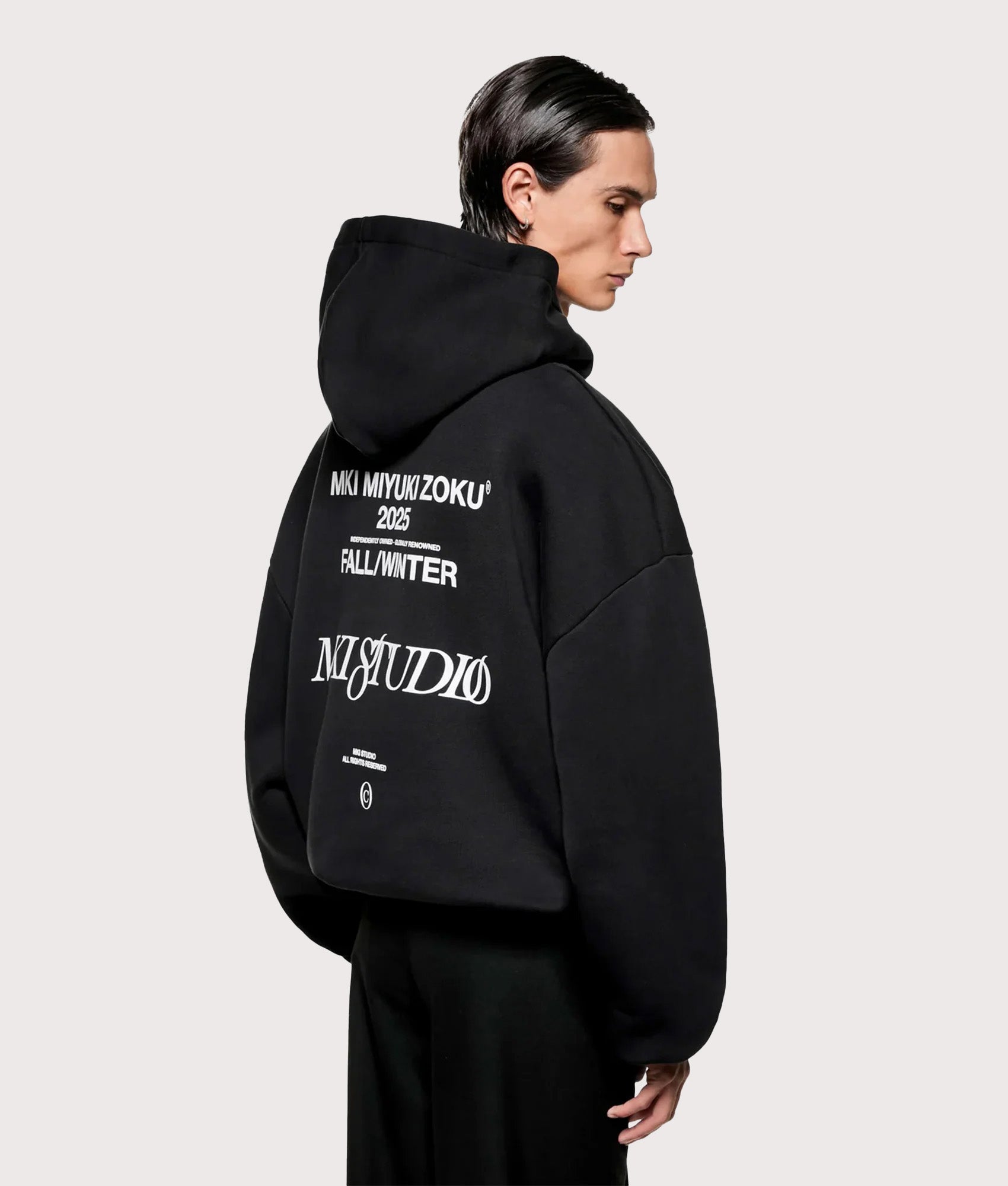 MKI MIYUKI ZOKU Script hoodie in Black at EQVVS Menswear. Angled model back shot.