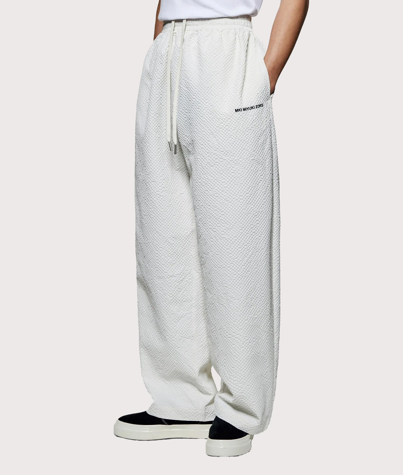 MKI MIYUKI ZOKU Seersucker Wide Leg Trousers in Bone at EQVVS menswear. Angled model front shot.