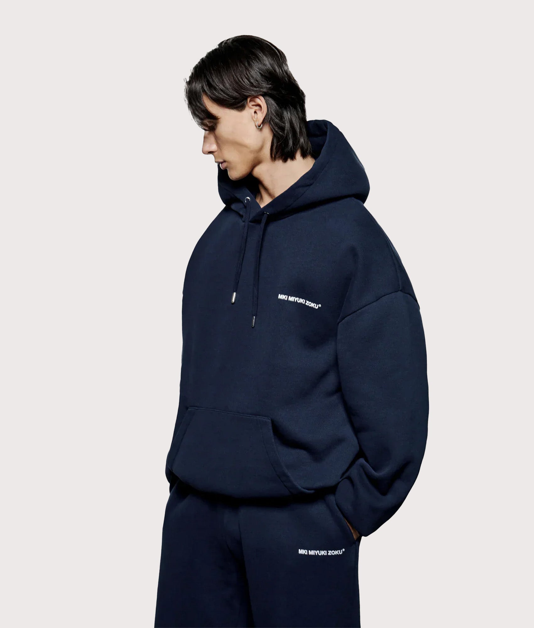 MKI MIYUKI ZOKU Oversized Uniform Hoodie in Navy at EQVVS Menswear. Angled model back shot.