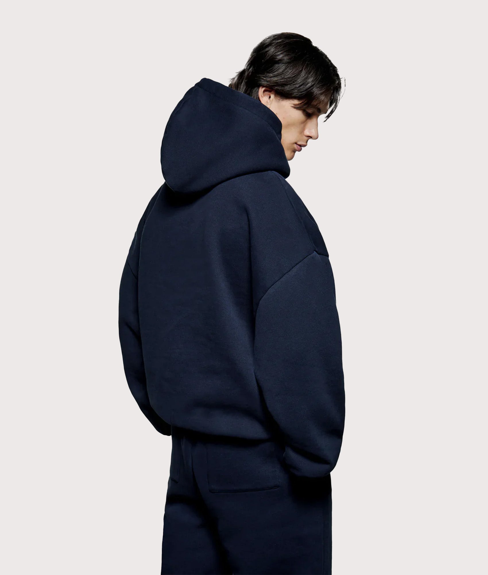 MKI MIYUKI ZOKU Oversized Uniform Hoodie in Navy at EQVVS Menswear. Angled model back shot.