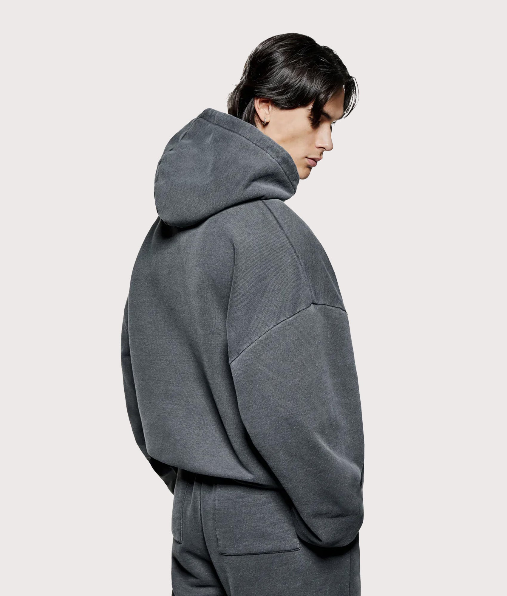 MKI Miyuki Zoku Oversized Uniform Hoodie in Pigment Black at EQVVS Menswear. Angled model back shot.